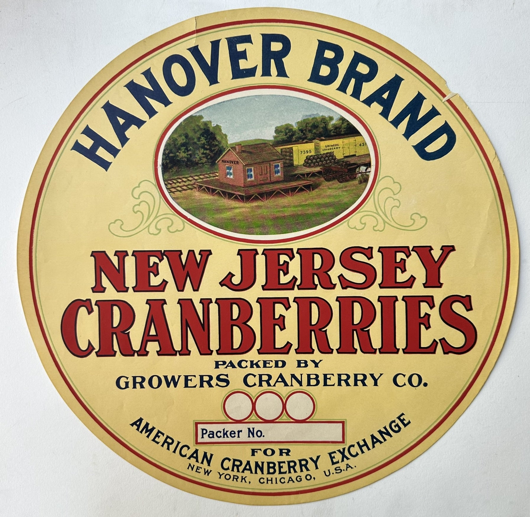 A vintage round label for "Hanover Brand New Jersey Cranberries," packed by Growers Cranberry Co., and distributed by American Cranberry Exchange for New York, Chicago, U.S.A. The label features a central illustration of a train station and freight cars in a rural setting, with the text "Hanover" visible on the station building