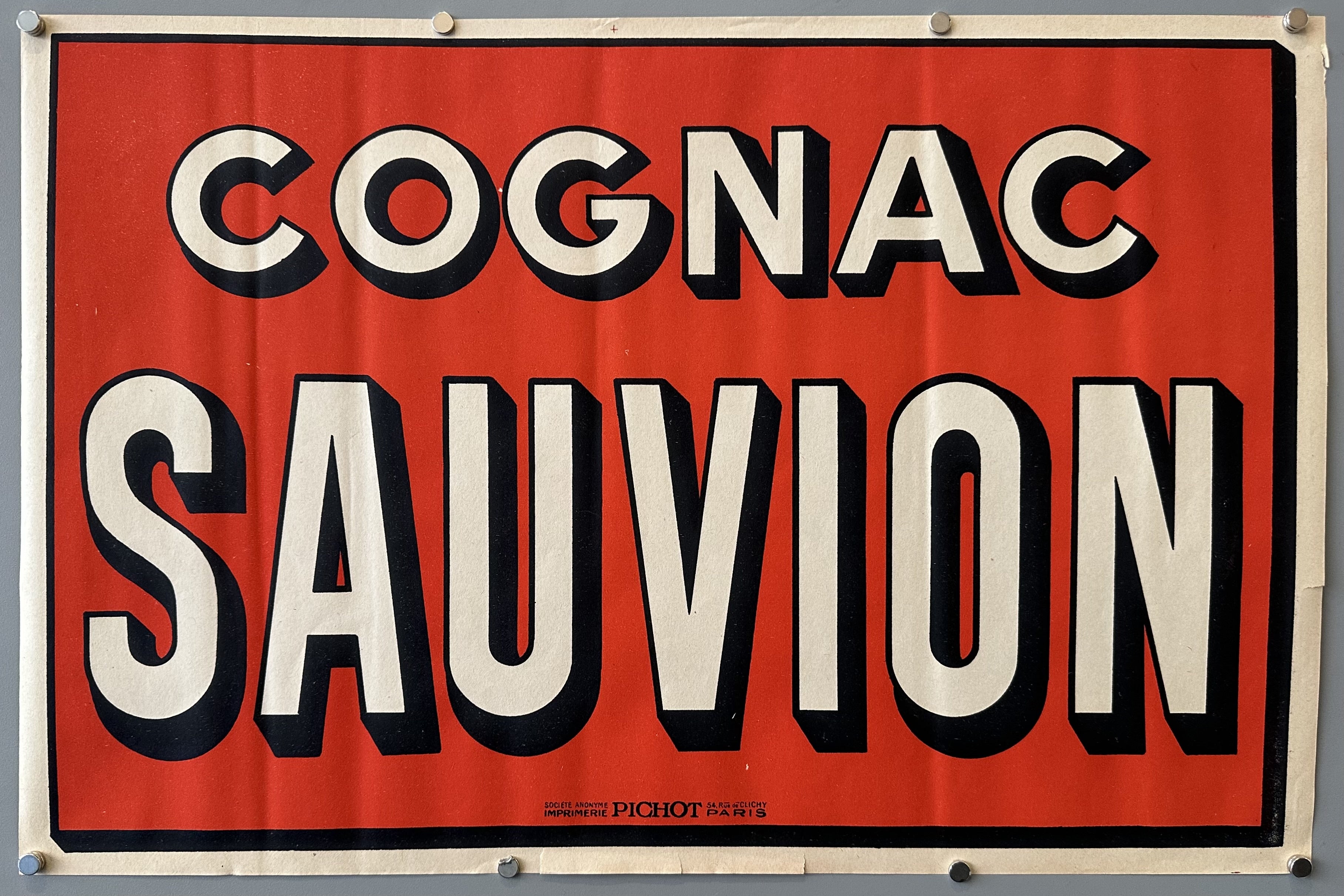 Red horizontal poster with white text and black border around text for Cognac Sauvion.