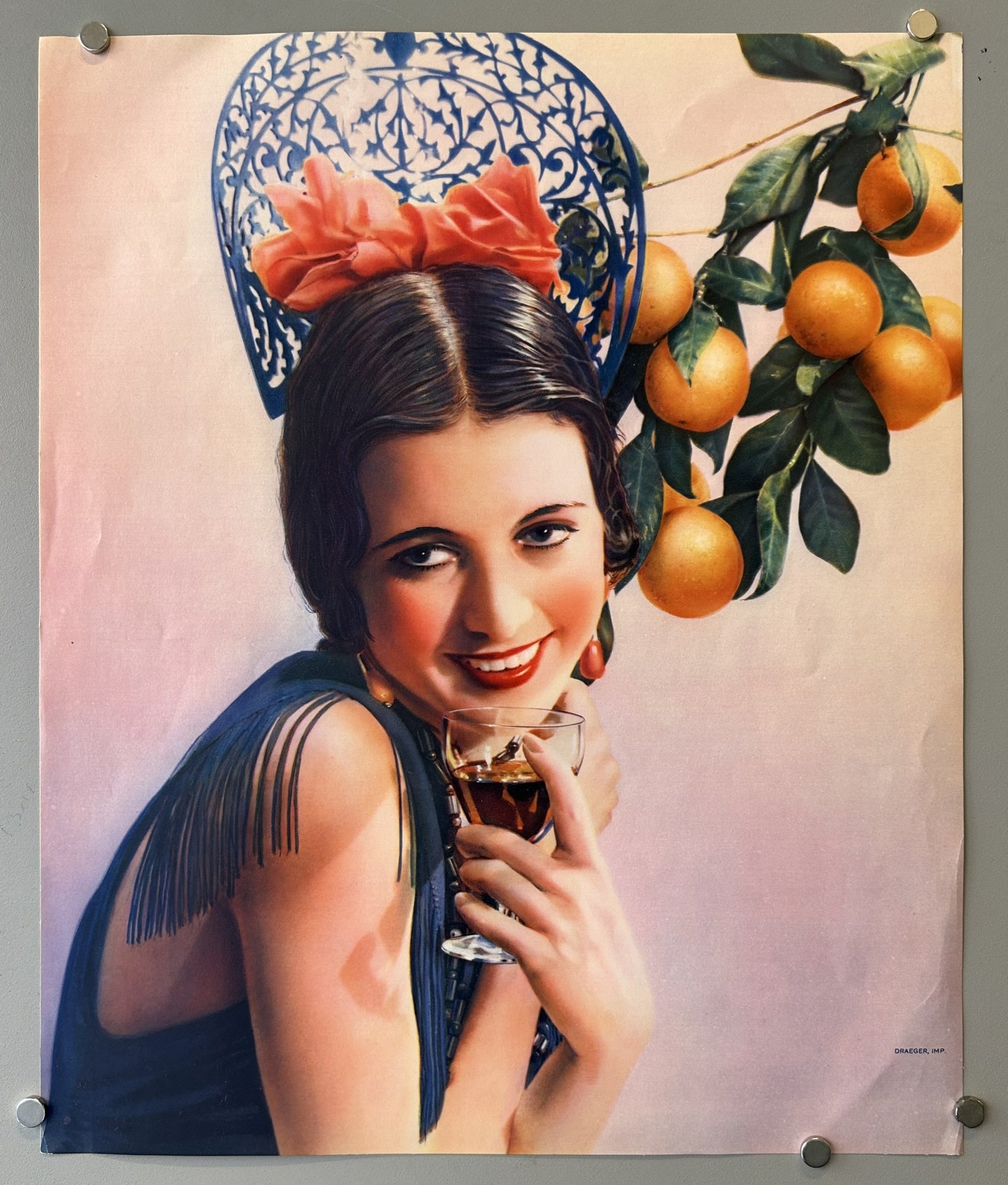 Woman with flower in her hair and oranges in the background carrying a glass of liquor.