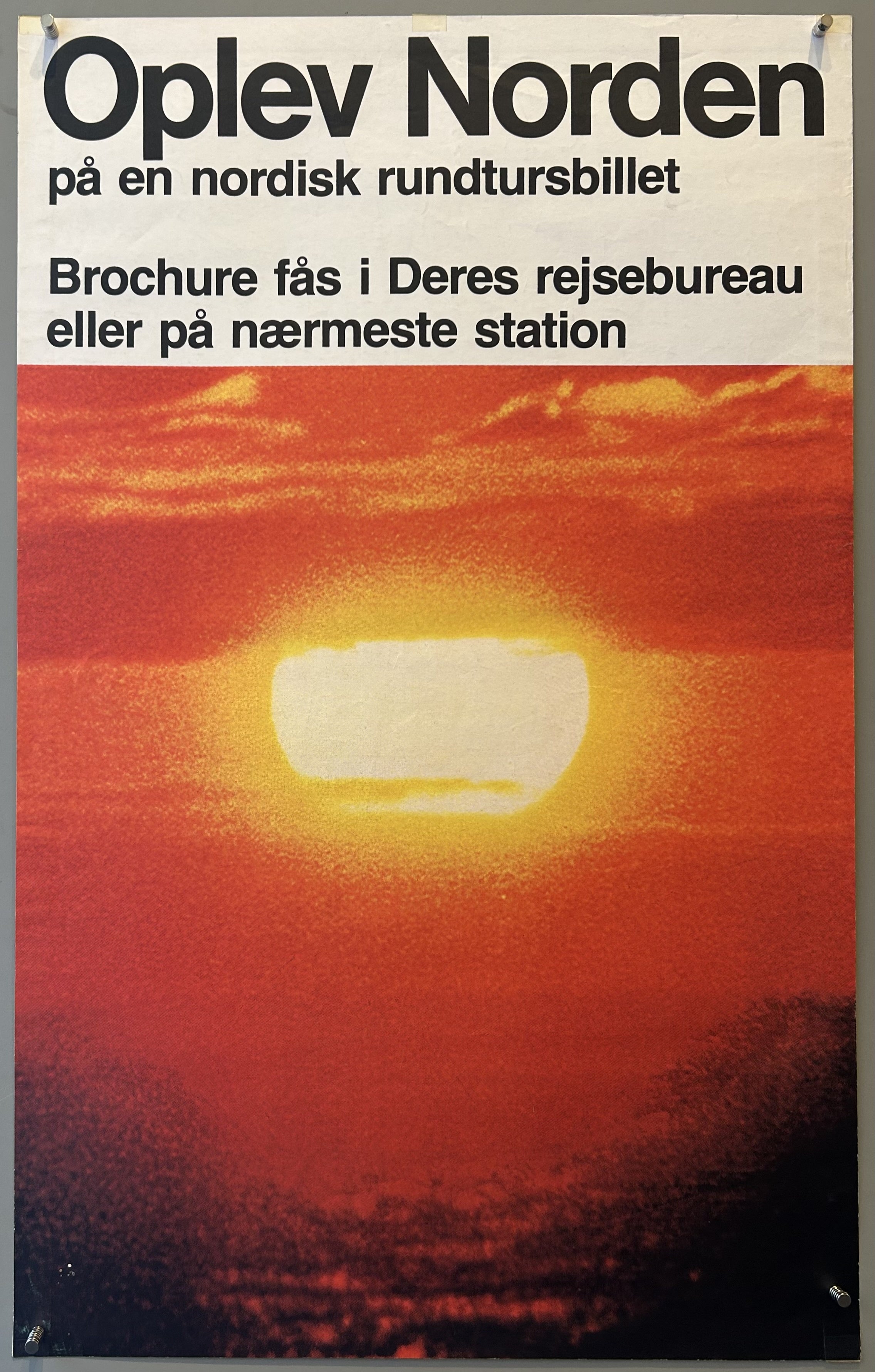 travel poster with a vibrant sunset or sunrise scene over a body of water, featuring a large, bright orange and yellow sun against a red and orange sky.