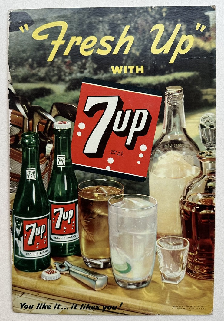 A vintage 7 Up advertisement featuring the tagline 'Fresh Up with 7 Up' against a tan background, with two green 7 Up bottles, a glass of amber liquid, a glass of clear liquid, a bottle opener, and a 7 Up logo card displayed on a wooden surface. The text 'You like it... it likes you!' is at the bottom.