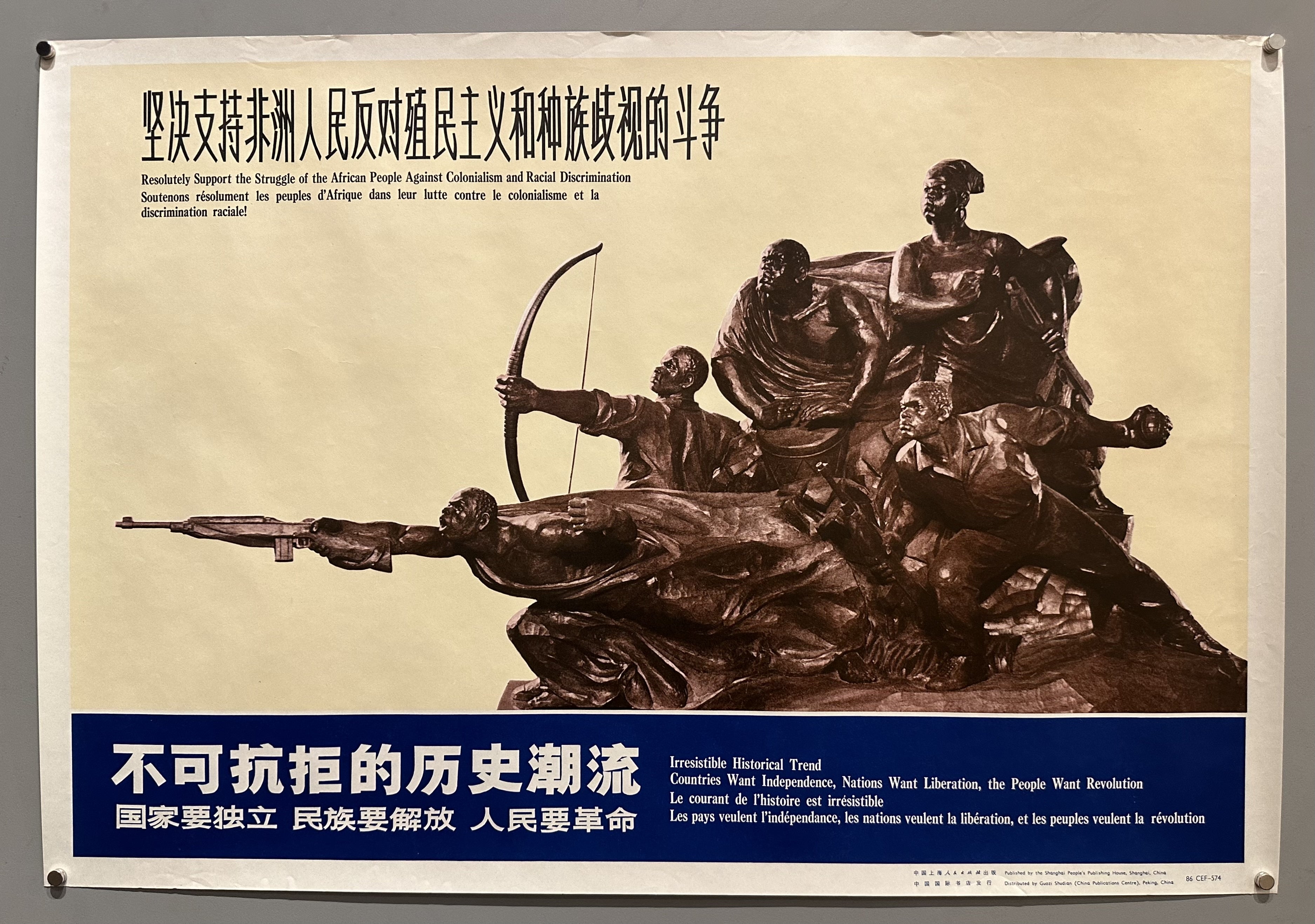 Statue against white background condemning the treatment of African peoples with blue border underneath it.