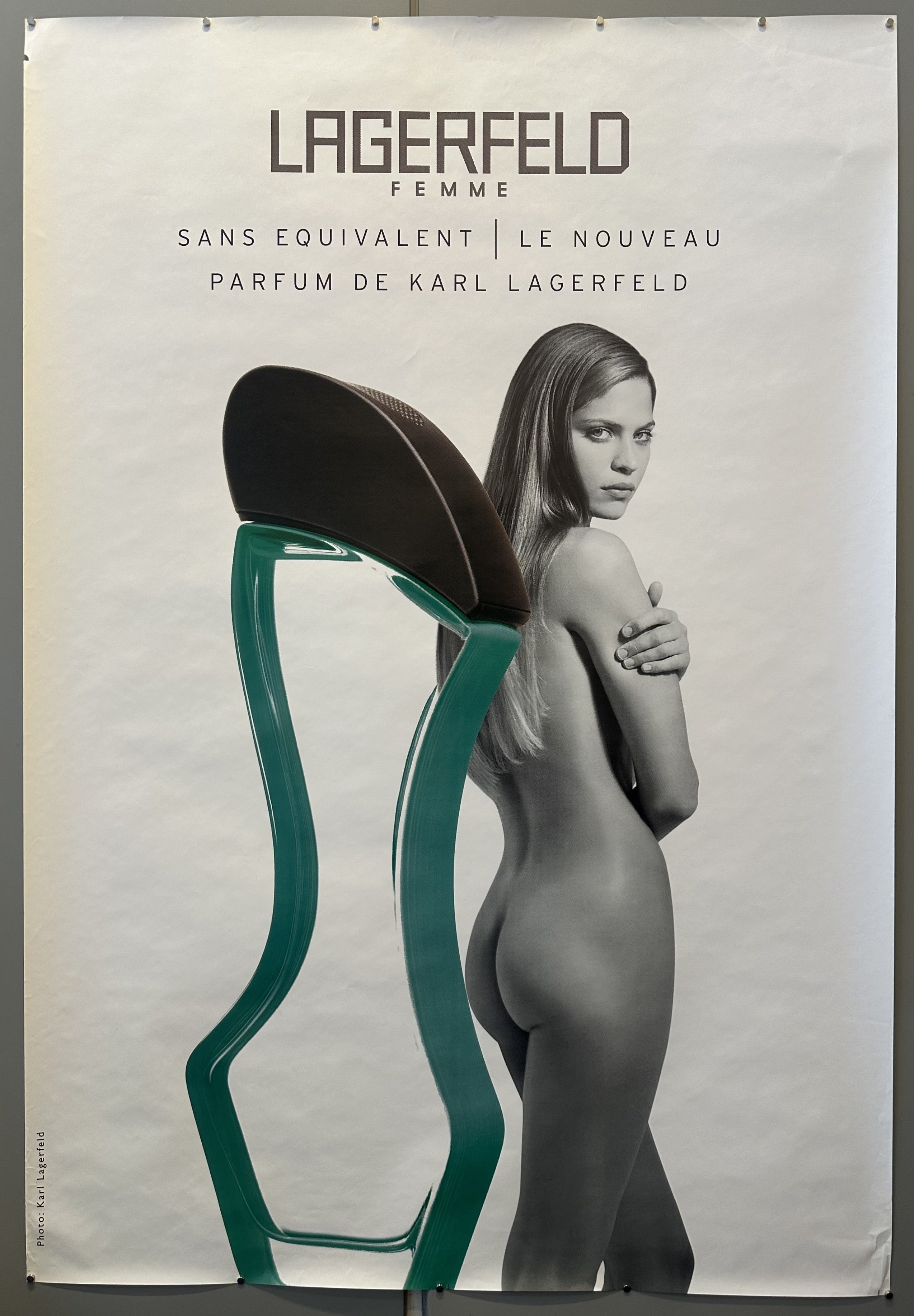 Black and white photograph of nude woman from back next to perfume bottle for Lagerfeld Femme.