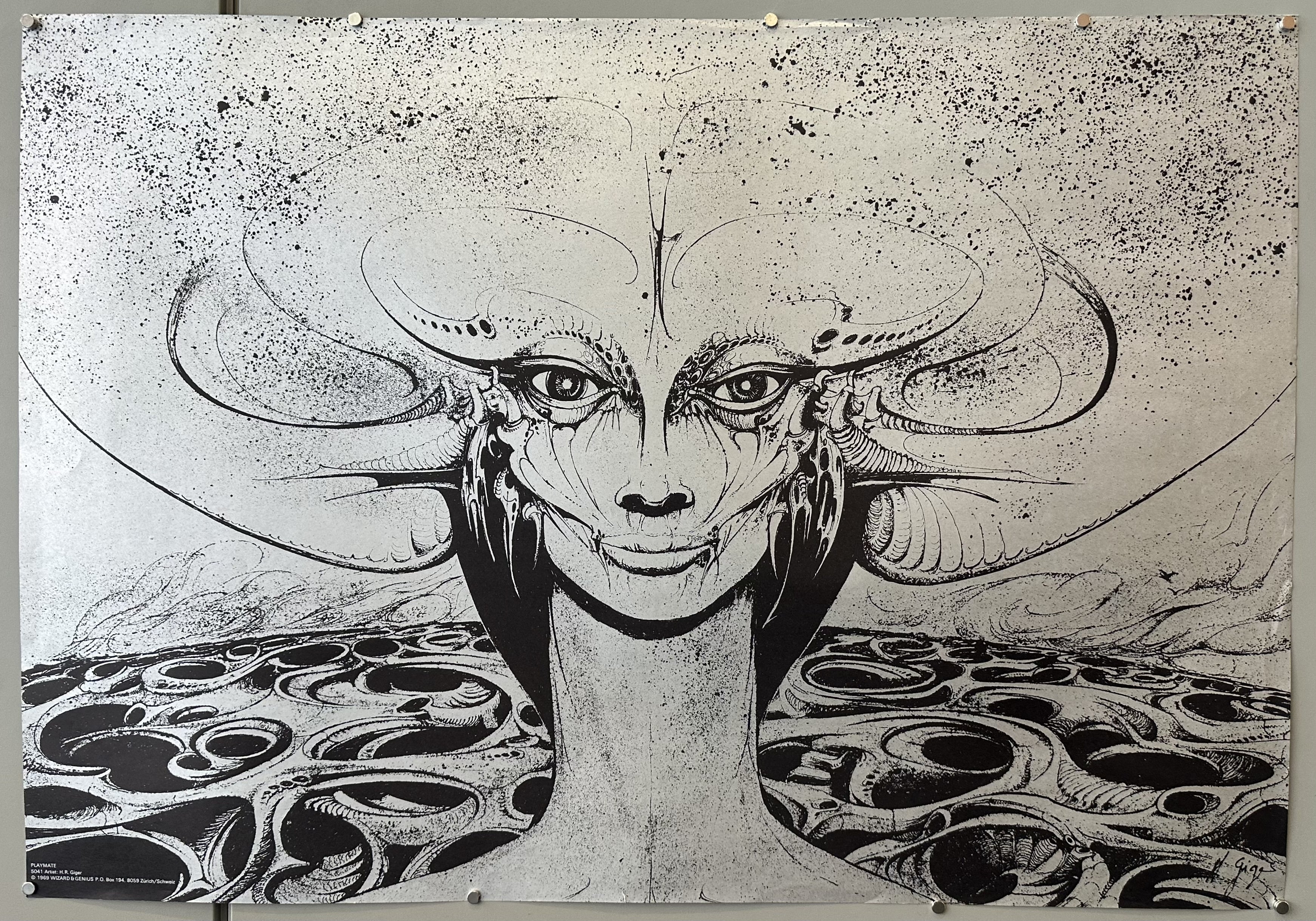 The poster in the image is H.R. Giger's "Playmate". This poster is from a portfolio of six posters issued in 1969 by Wizard & Genius.