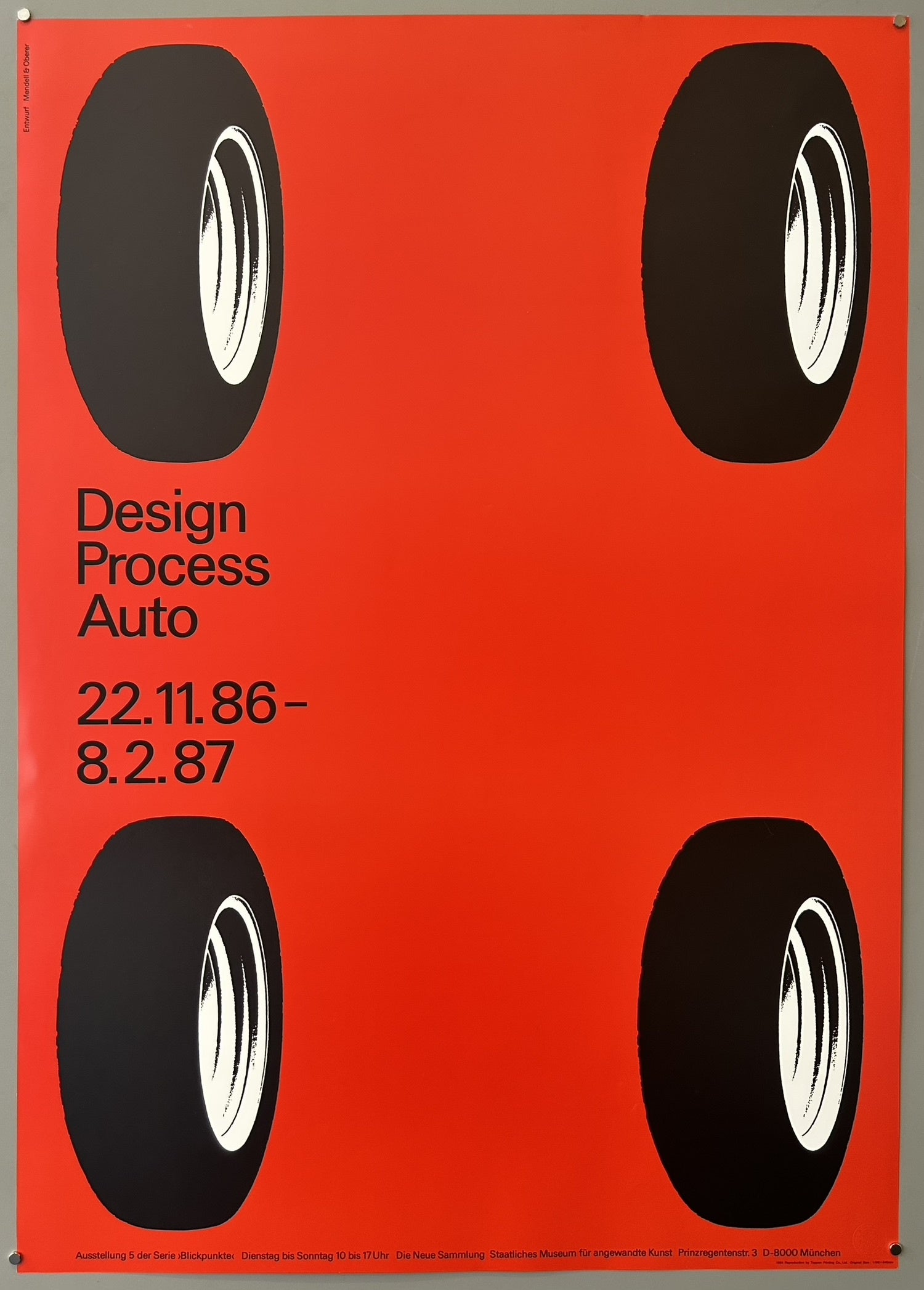Features four tires arranged in the corners against a solid red background, intentionally leaving the center vacant to allow the actual products to be revealed at the exhibition and to avoid favoring any particular automobile design.