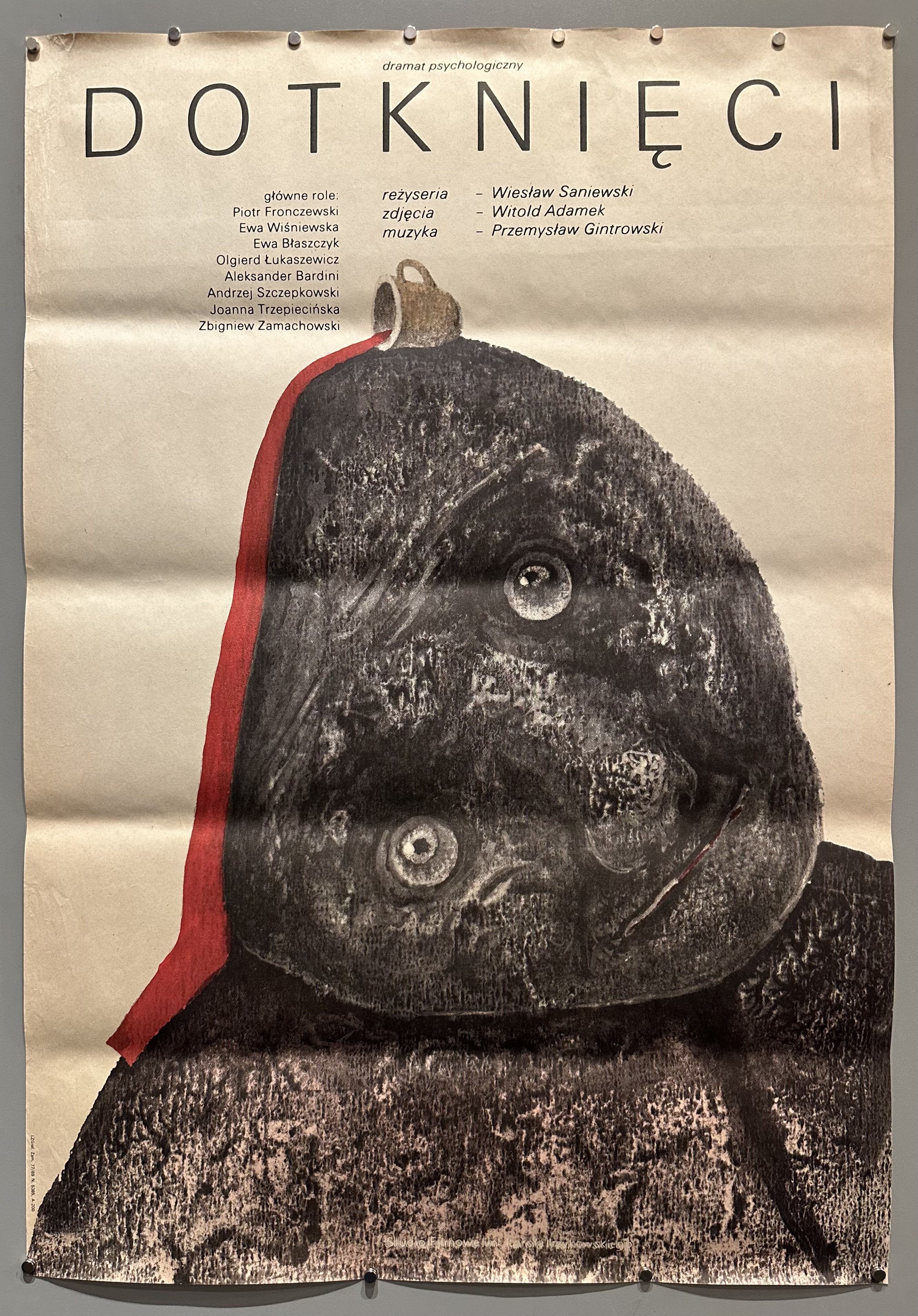 Grey figure with red blood dripping from a cup atop its head against white background in Polish film poster.