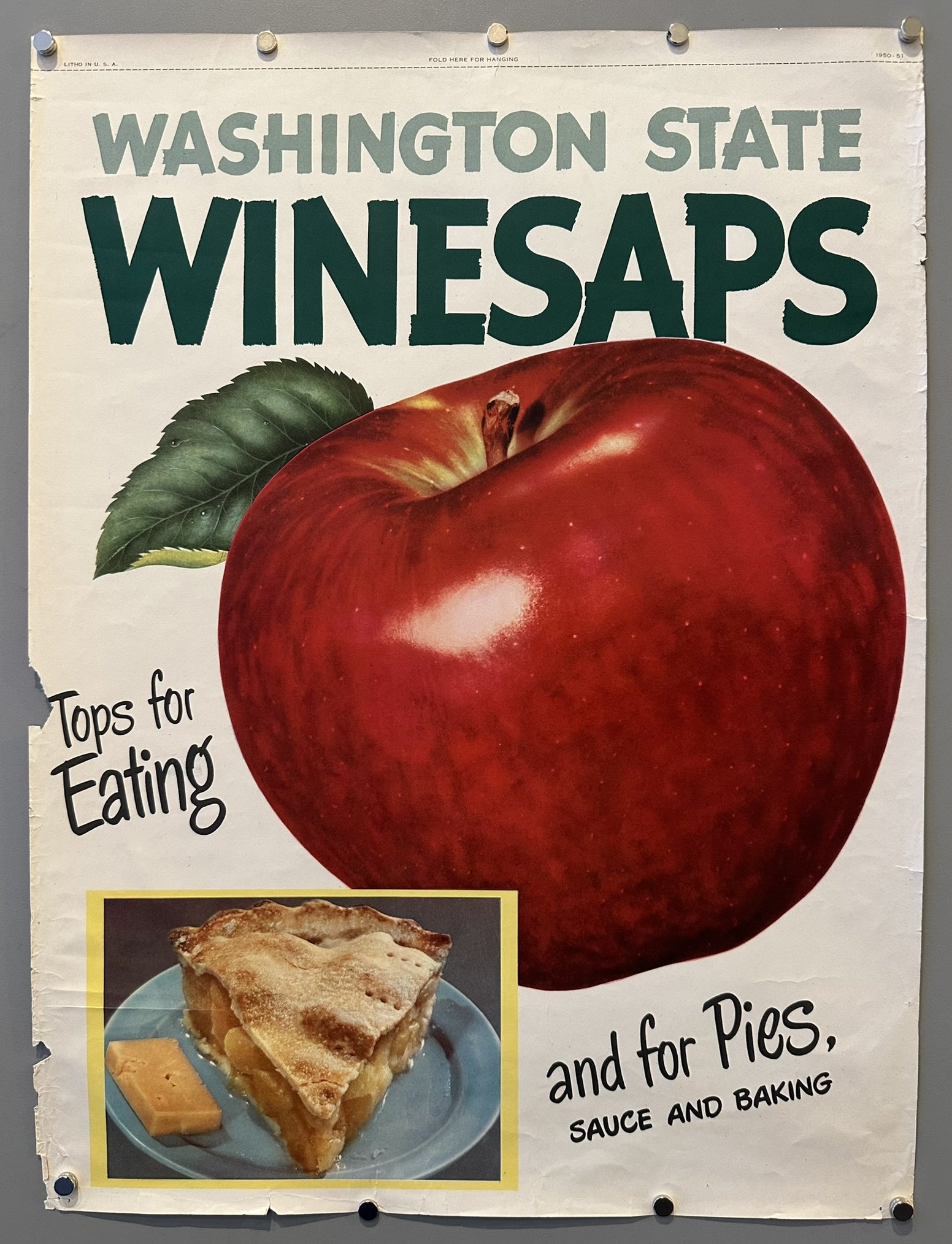 A vintage poster advertising "WASHINGTON STATE WINESAPS" apples. The poster features a large, vibrant red Winesap apple with a green leaf attached, and below it, a smaller inset image of a slice of apple pie with a piece of cheese on a blue plate.