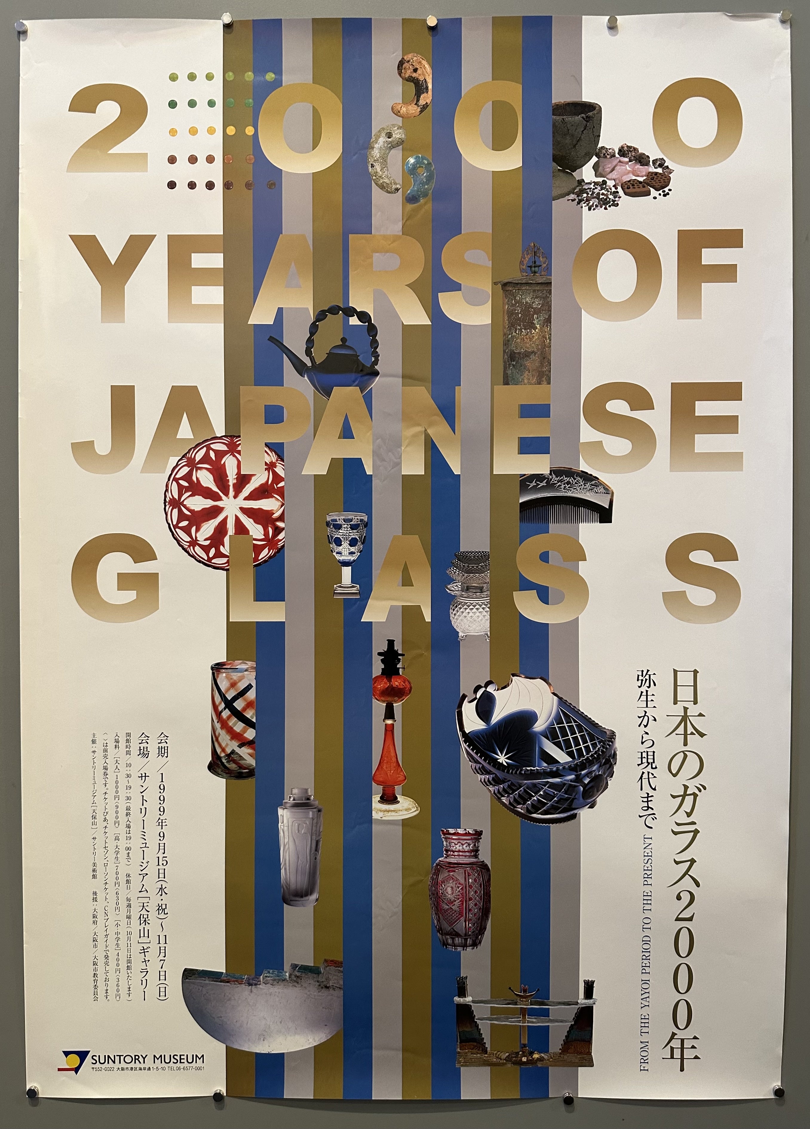 Various glass items are pictured with gold text interlaced throughout them in exhibition poster for Suntory Museum.
