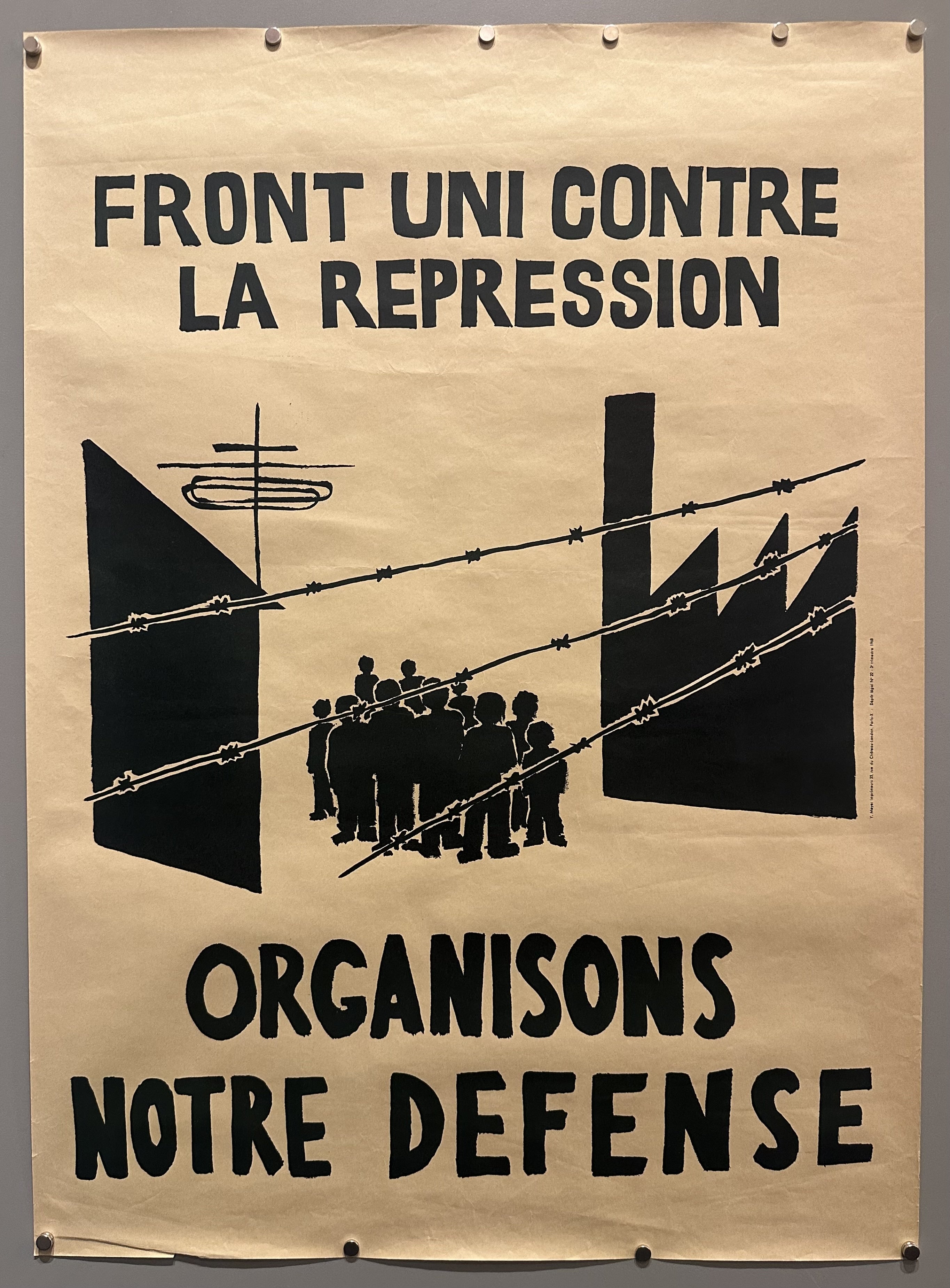 People stand behind barbed wire with imposing buildings surrounding them in this May 68 propaganda poster.