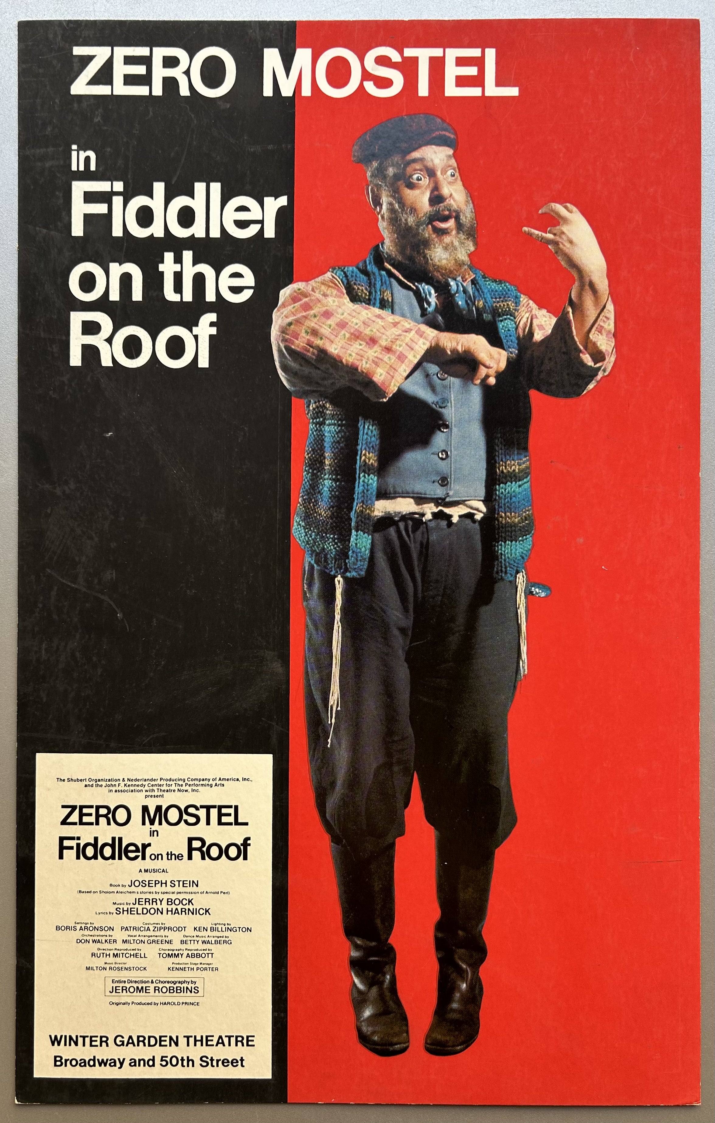 Red and black split color poster with Mostel on red side of it in costume and white text on black side to promote Fiddler on the Roof performance.