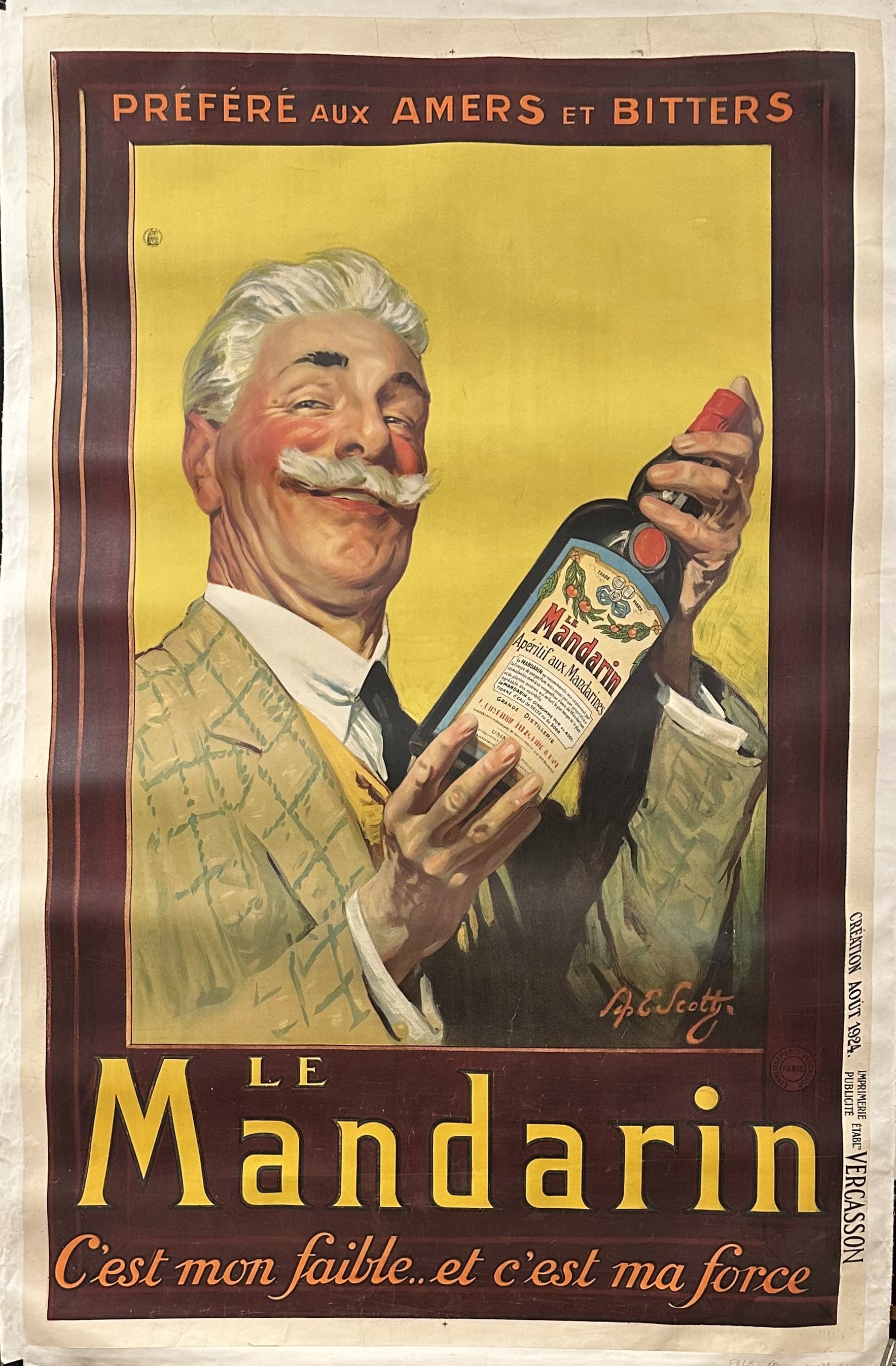 A man holds a bottle of Le Mandarin Apéritif aux Mandarines.