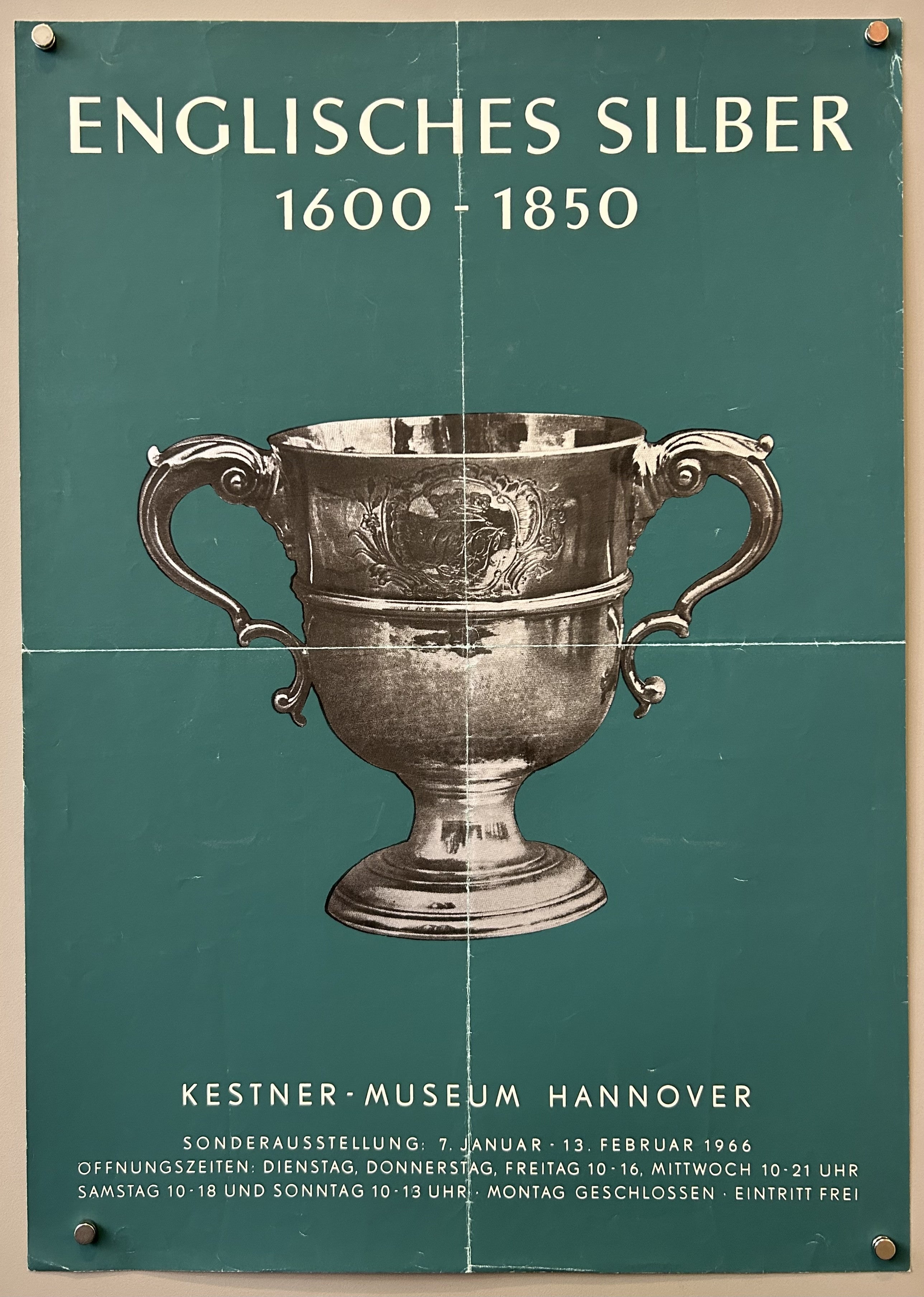 a dark green background and a black and white photograph of a large, two-handled silver trophy cup in the center.