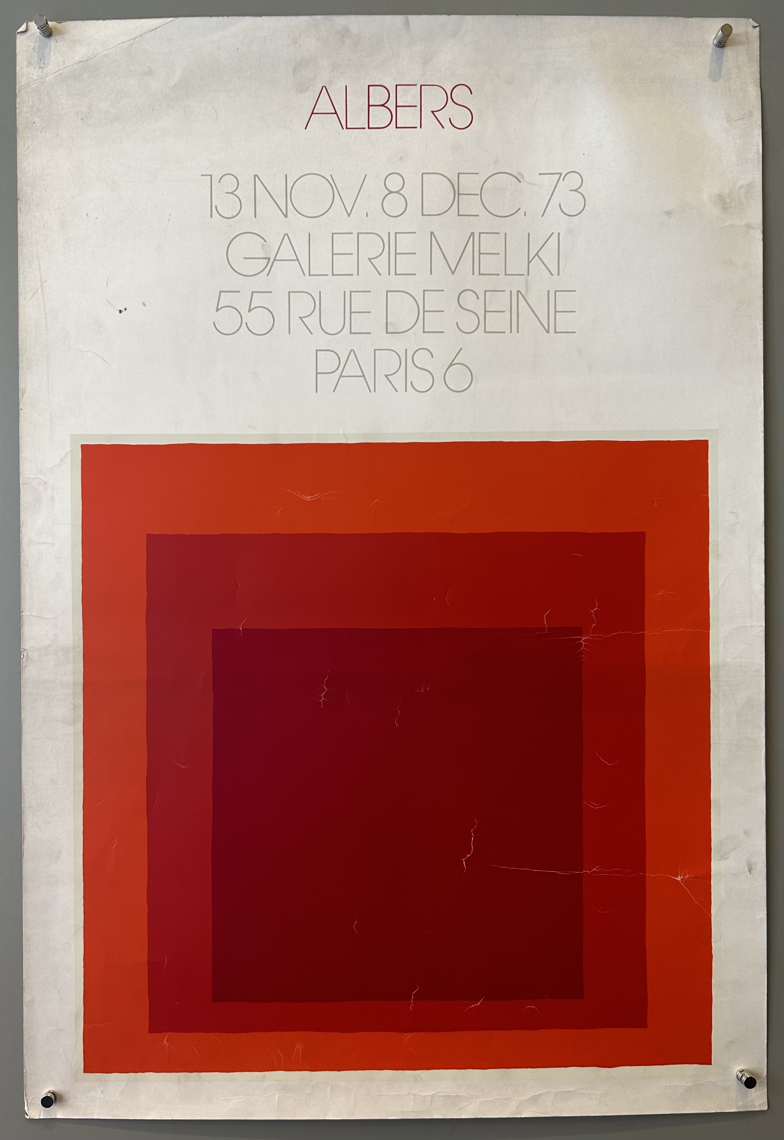 White poster with layered red squares in center and thin red and grey text above.