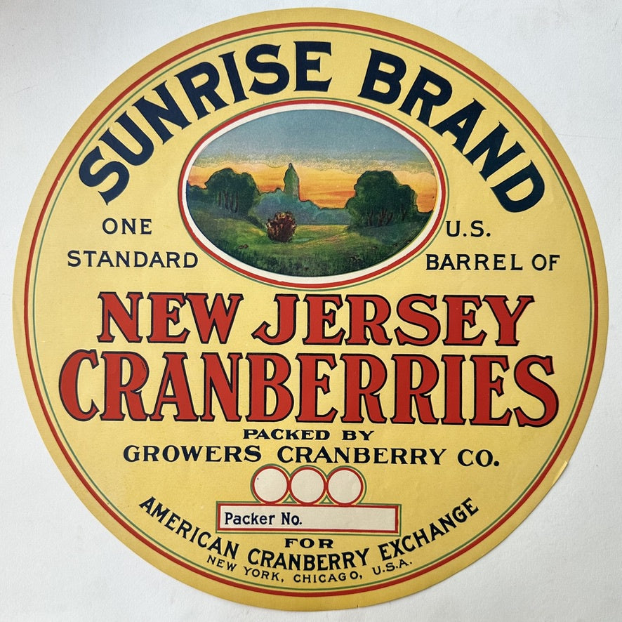 A vintage, circular yellow label for "SUNRISE BRAND NEW JERSEY CRANBERRIES," featuring a central oval illustration of a rural landscape with a sunrise. The label states "ONE STANDARD U.S. BARREL OF NEW JERSEY CRANBERRIES," "PACKED BY GROWERS CRANBERRY CO.,"