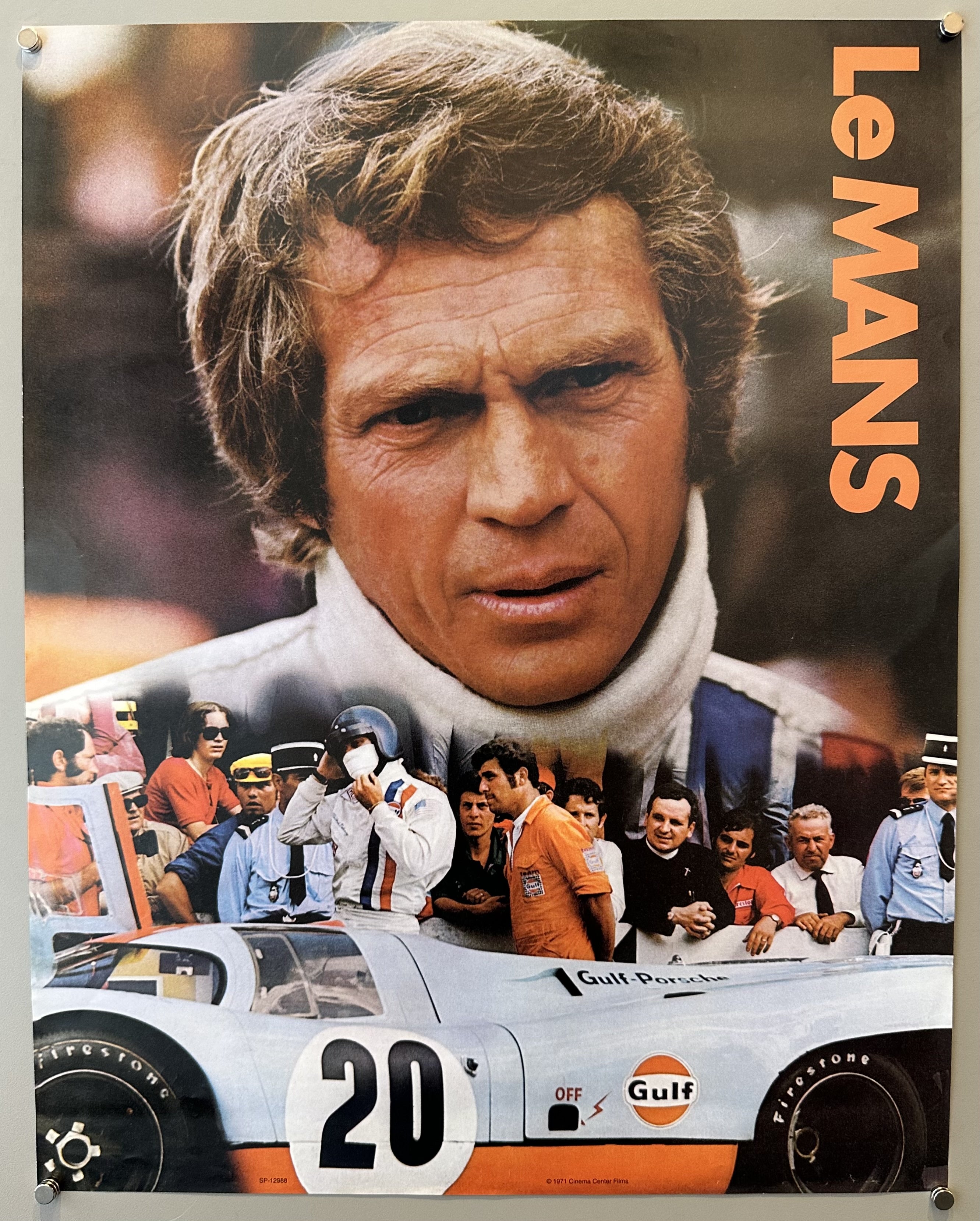Portrait of Steve Mcqueen with a serious expression with a cra and people in a line