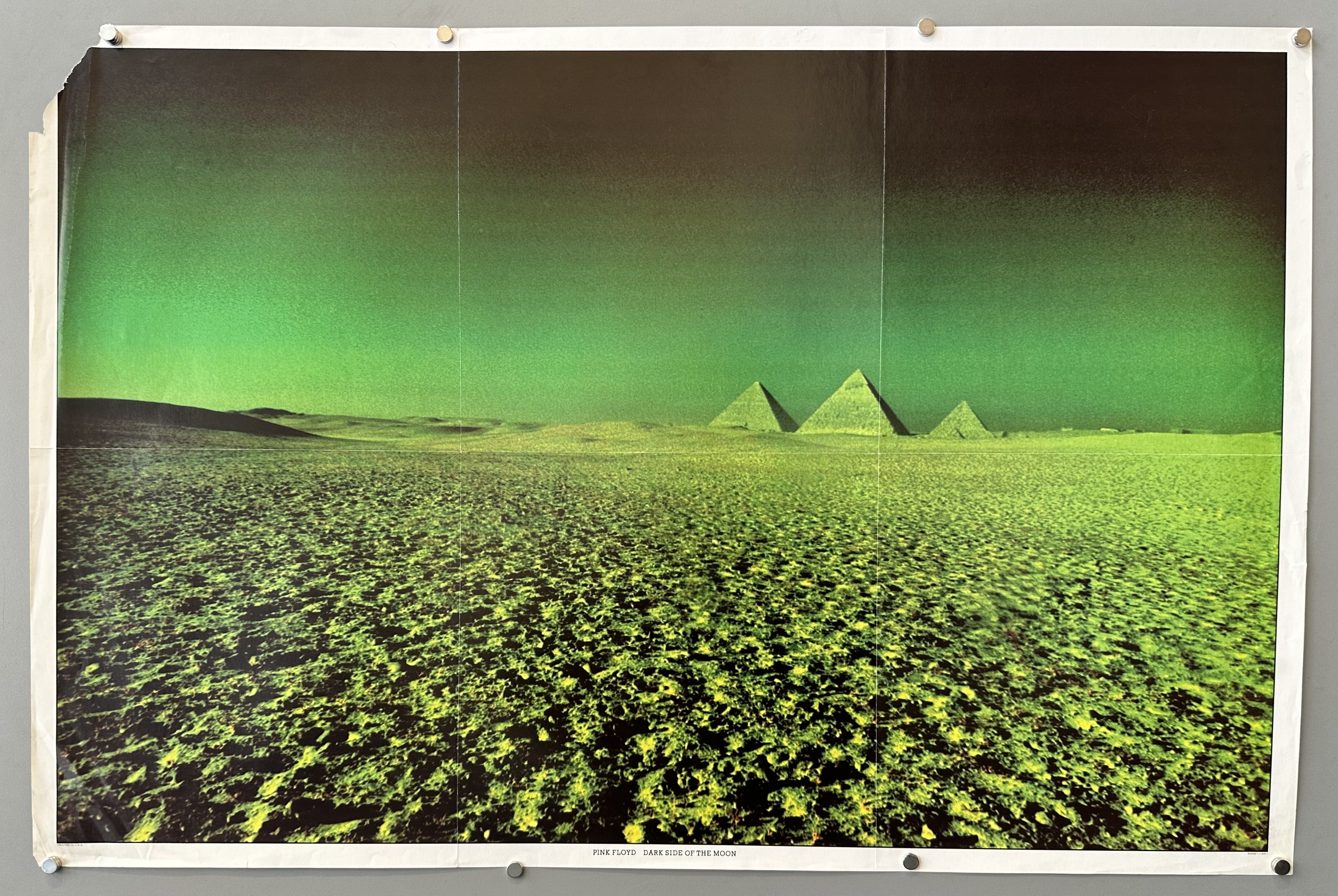 A wide shot of the Giza pyramids in Egypt under a dark green sky, with the foreground showing a textured, dark green landscape