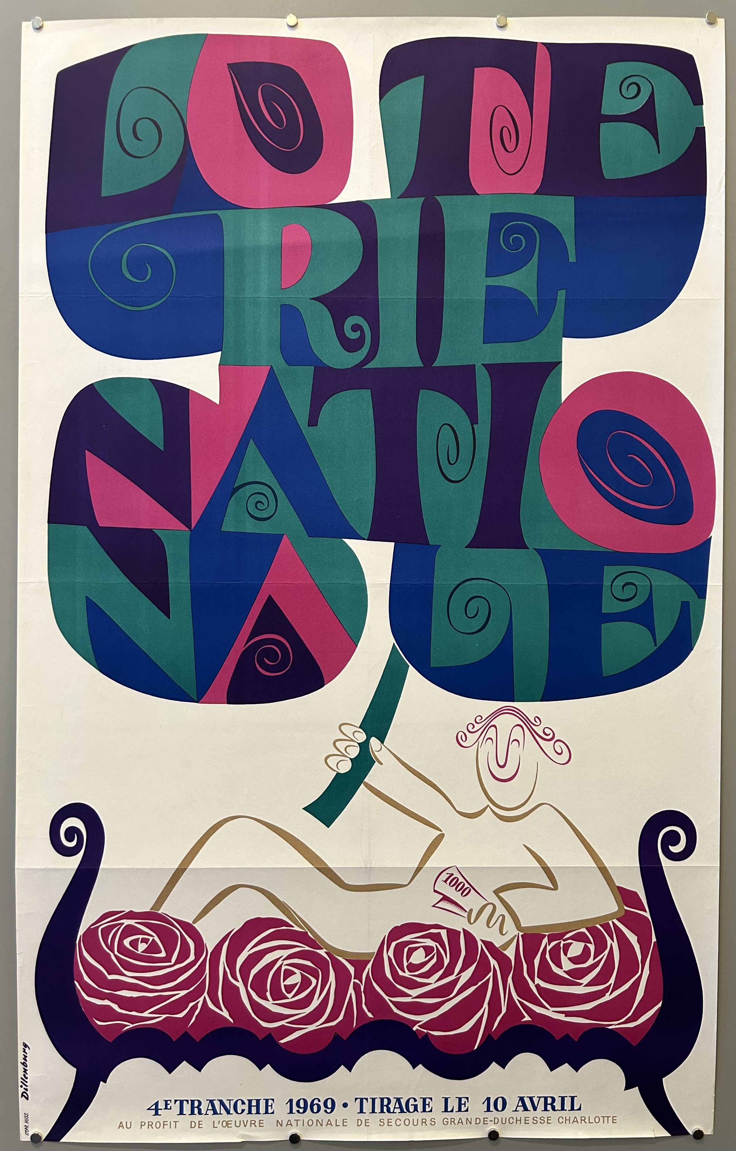White Loterie Nationale poster with woman holding up a green, blue, and pink flower spelling out 'Loterie Nationale' while laying on a bed of roses.