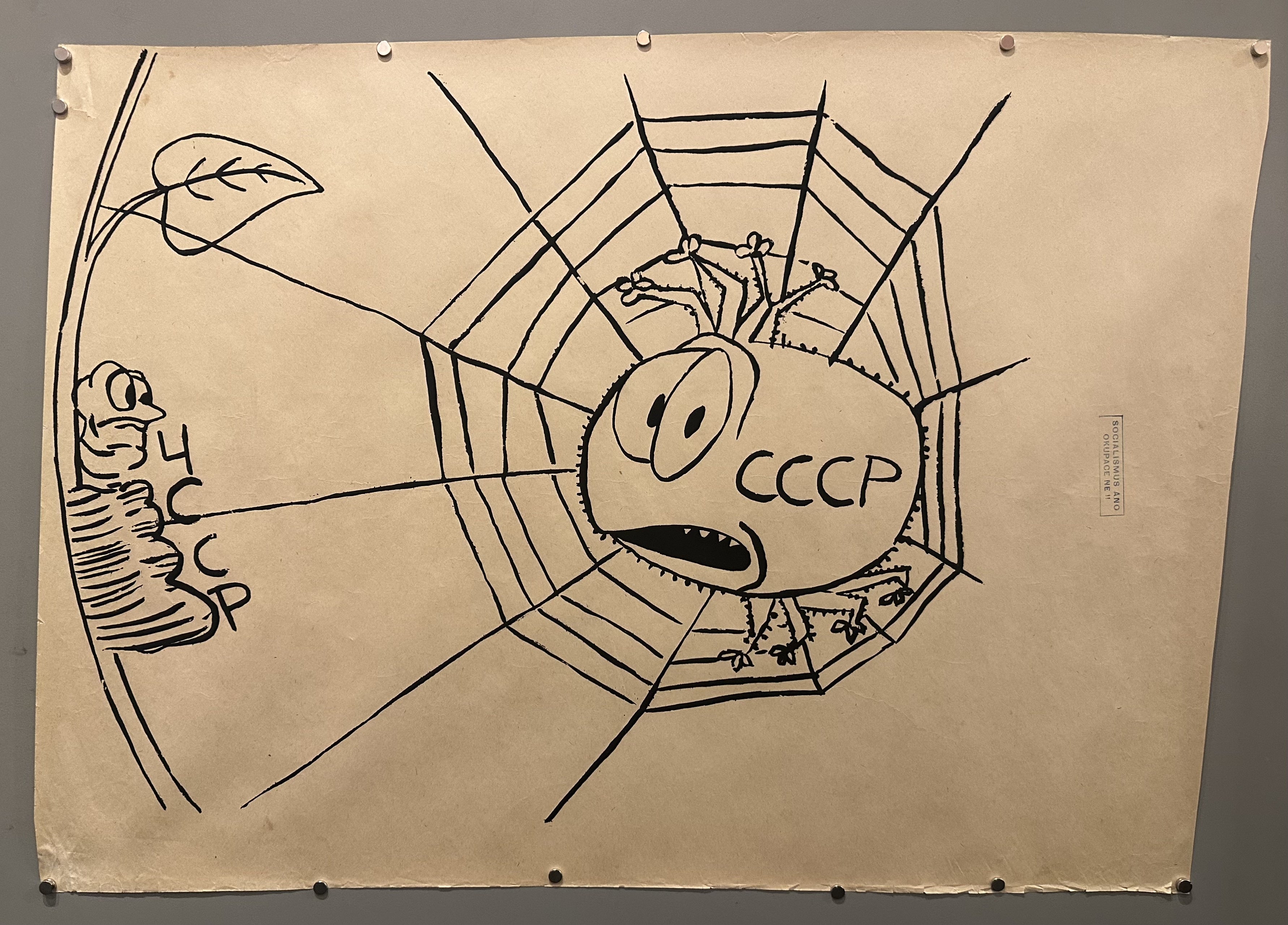 A spider is caught in a web in this political poster from Prague Spring.