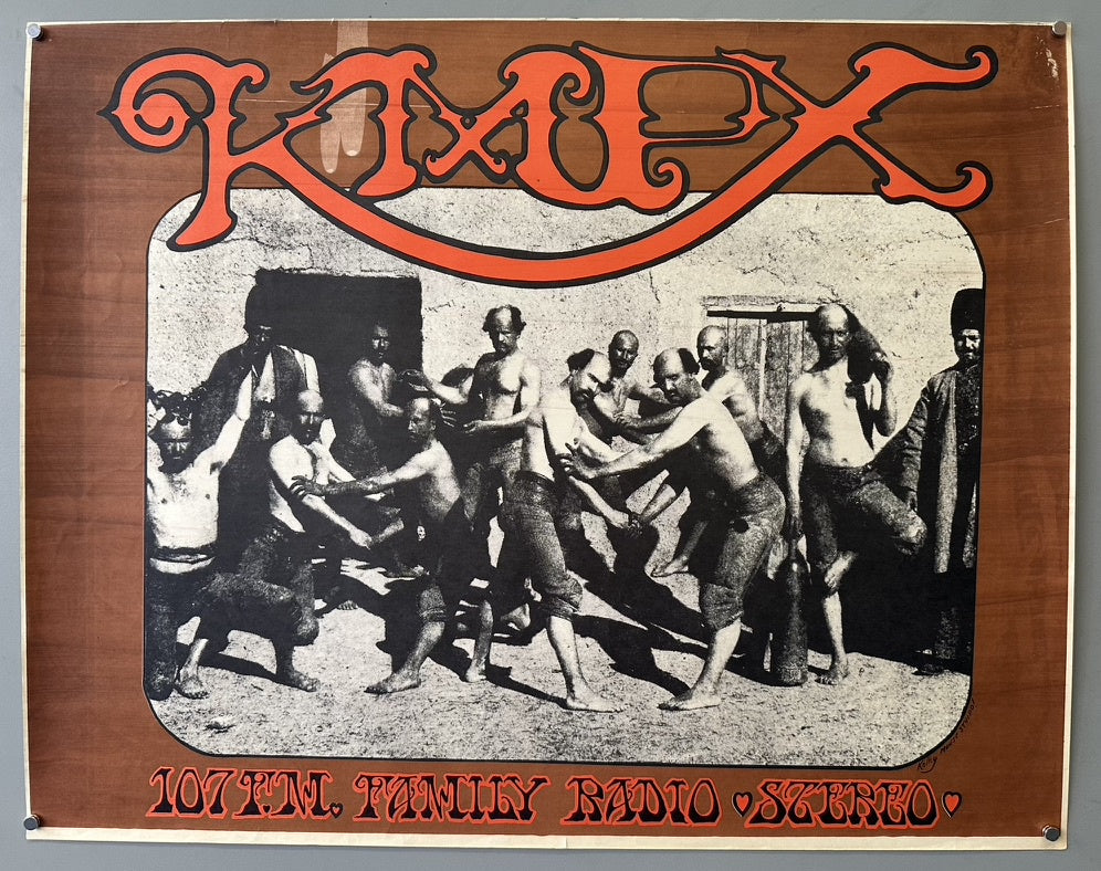 A brown KMPX 107 FM Family Radio Stereo poster featuring a black and white image of several men in various states of undress, engaged in what appears to be a physical struggle or game, set against a light-colored wall.