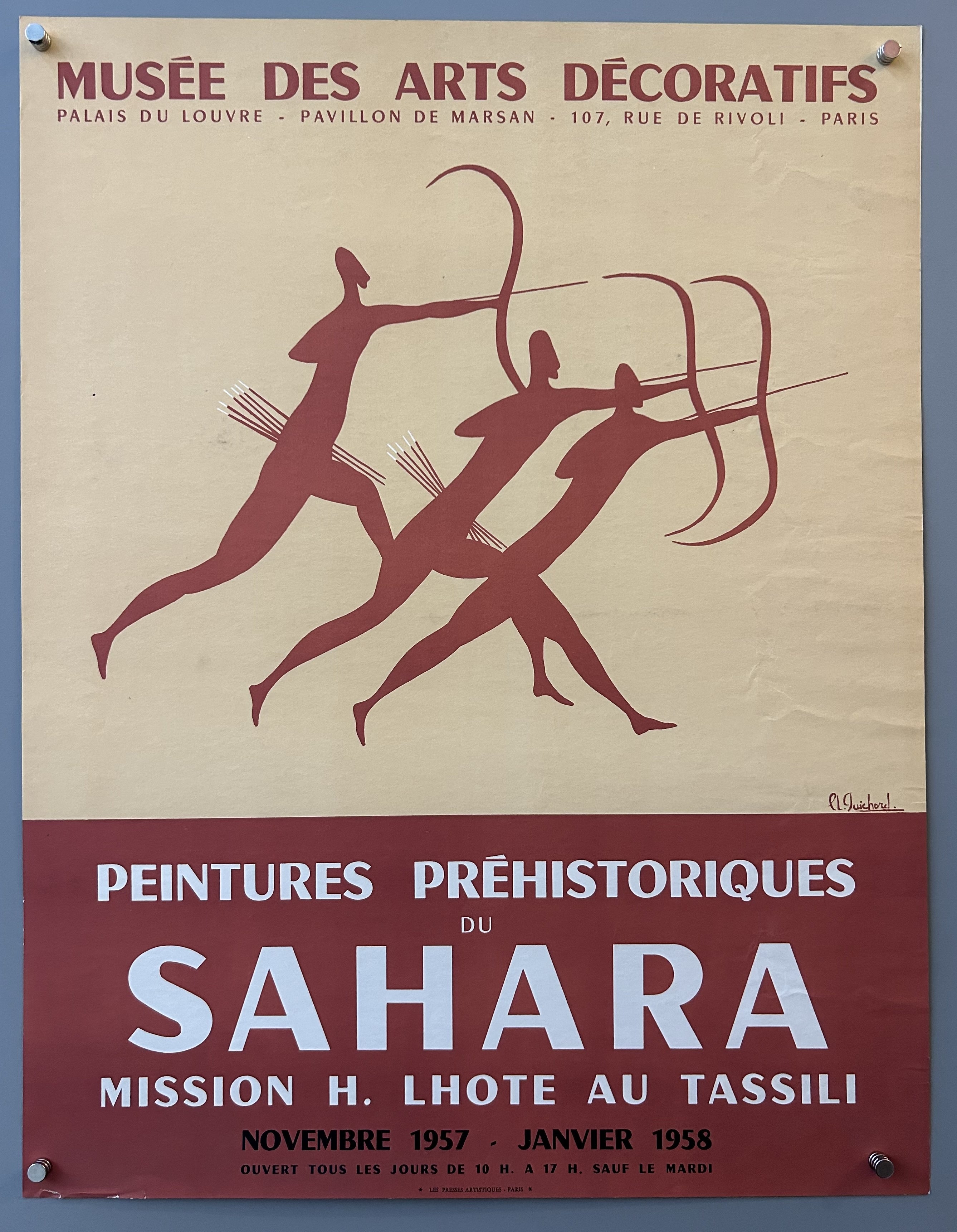 Poster promoting prehistoric art exhibition at a French museum with three cavemen shooting arrows and red borders.