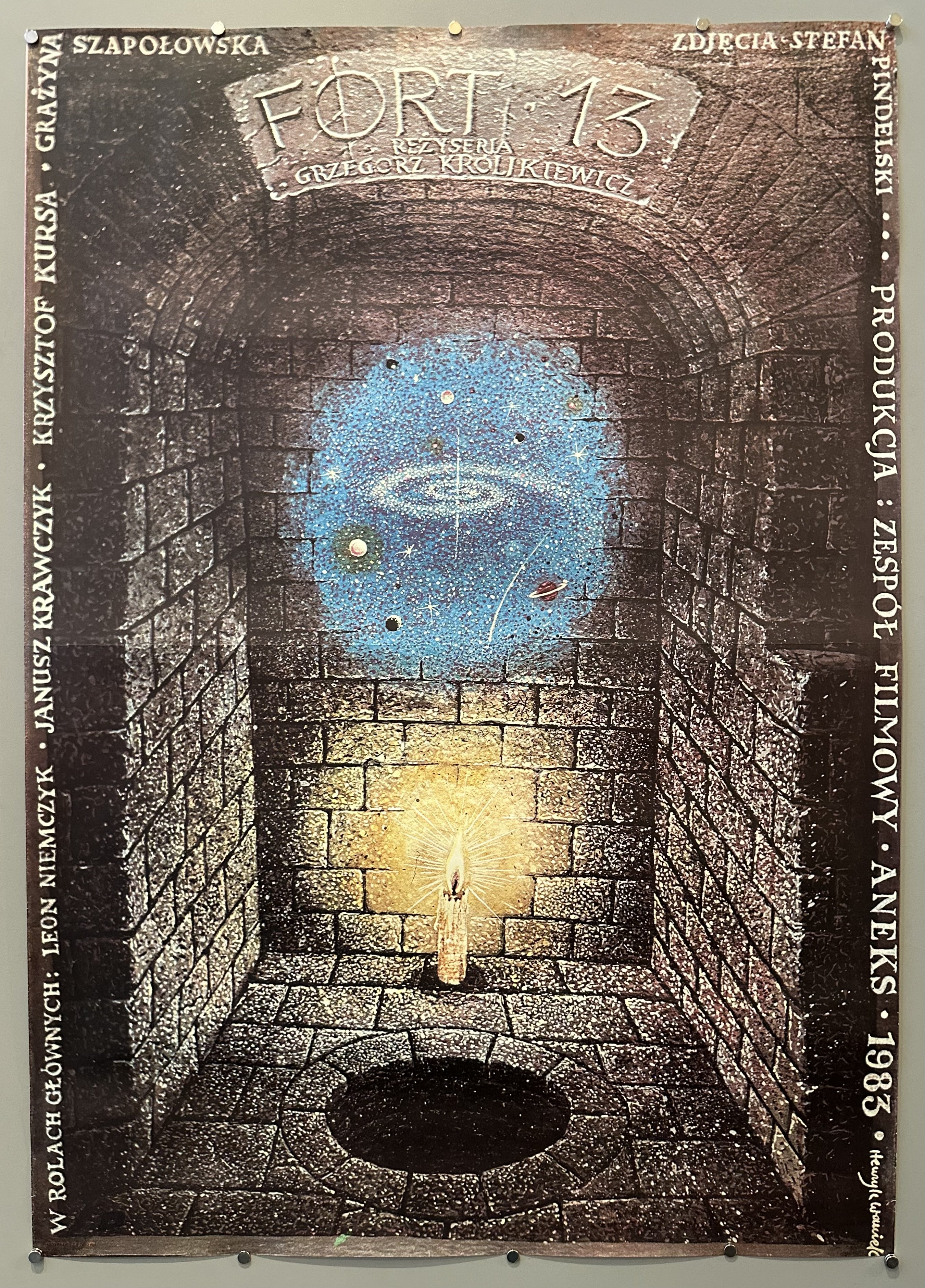 Polish film poster with a bricked room , centered is a galaxy and a candle lit. surrounding the border of the poster in the text translating to the cast playing in the film.