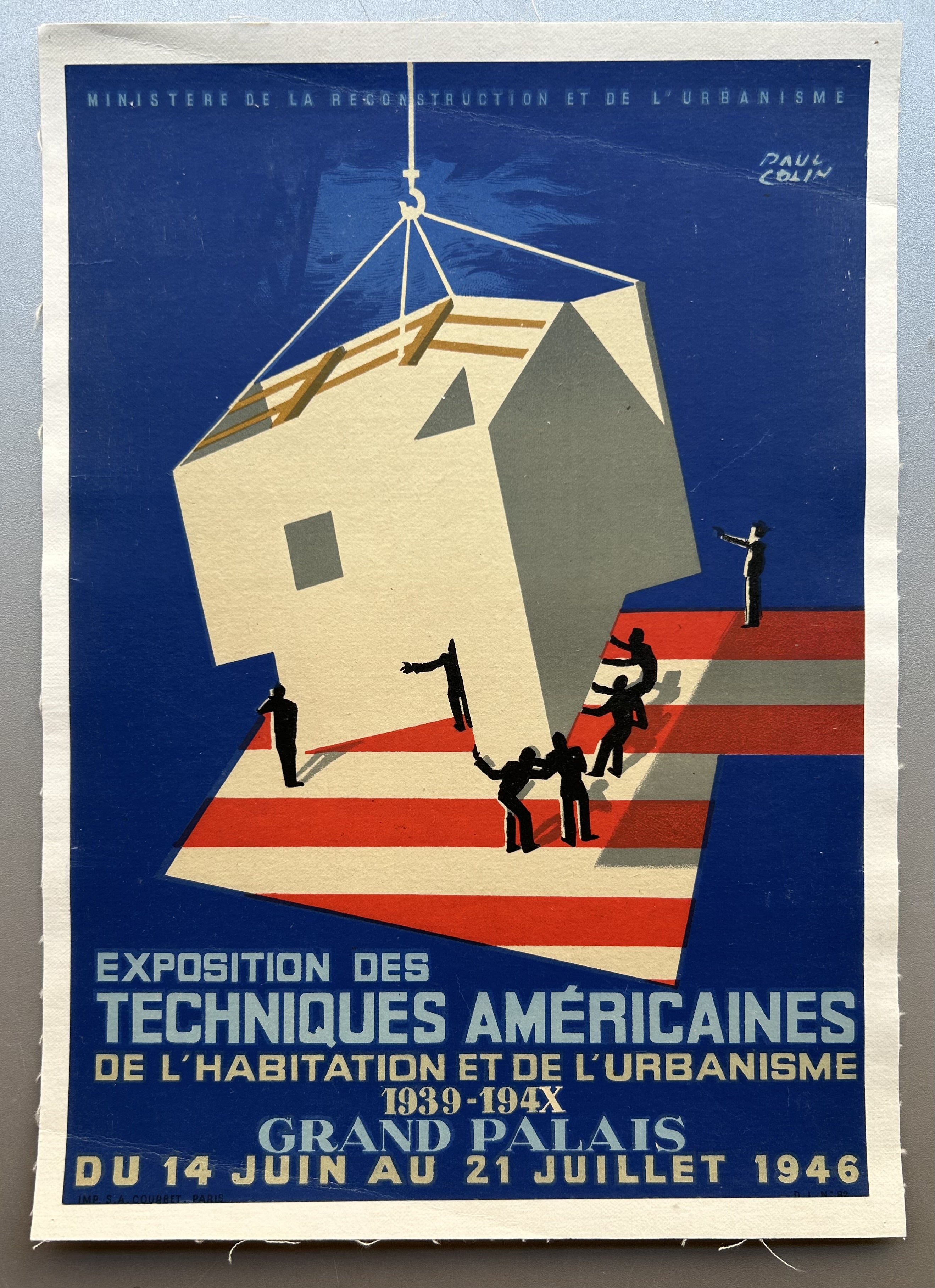Poster by Paul Colin featuring an American flag and workers lowering a house onto the stripes to promote industrial exposition.