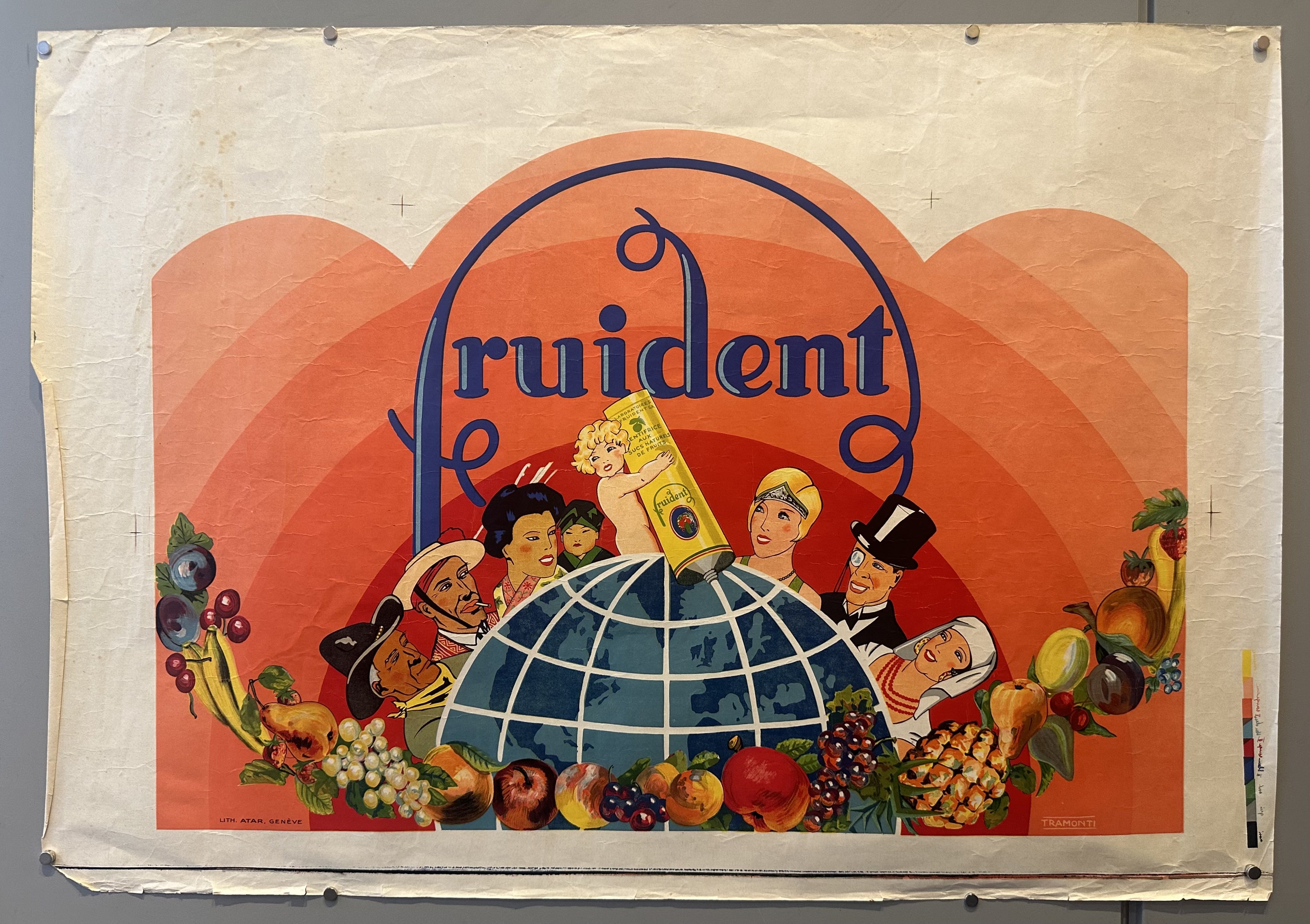 A child squeezes a tube of Fruident toothpaste onto a globe with fruits surrounding her and other people of different cultures.