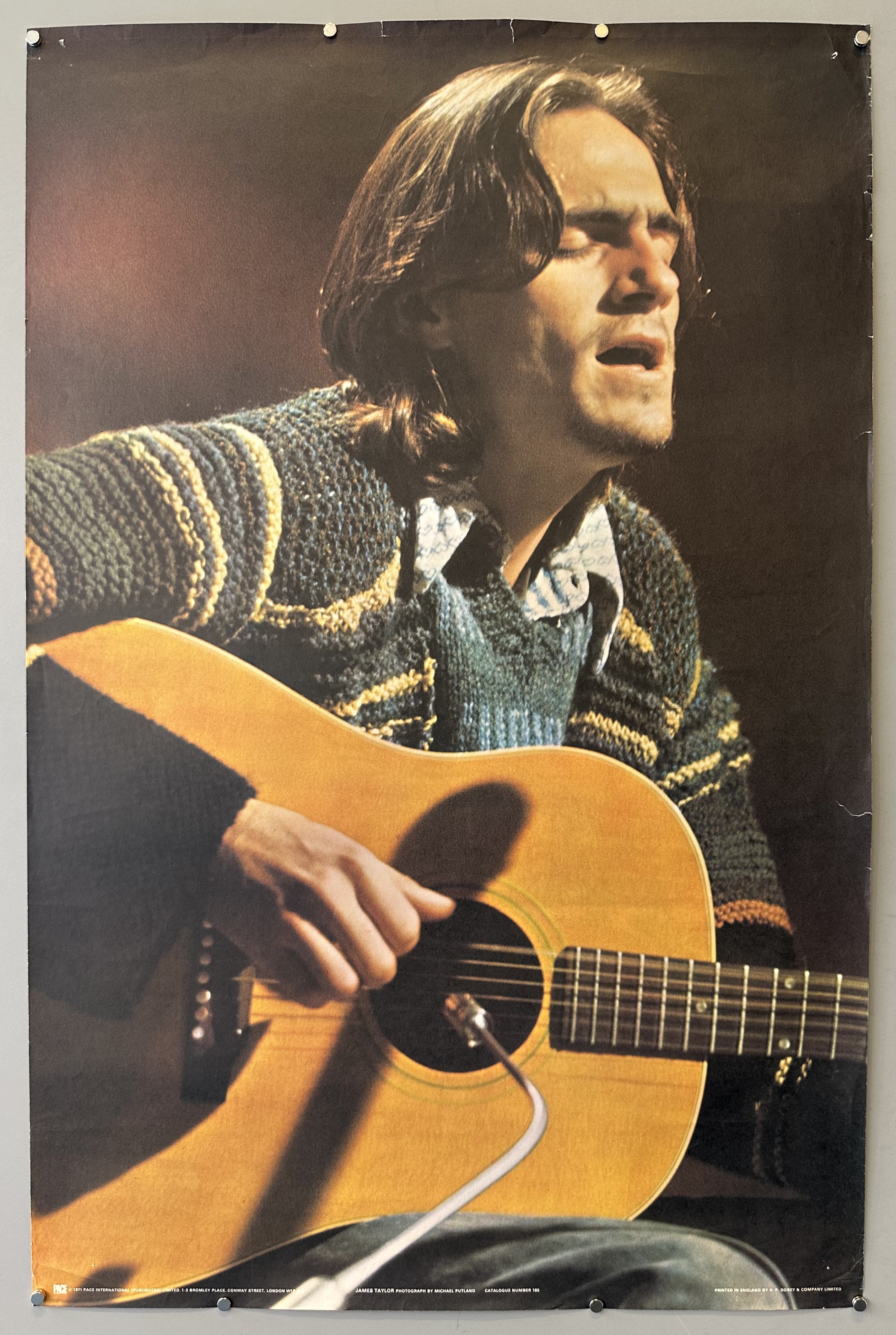 Photograph of James Taylor singing and playing guitar.