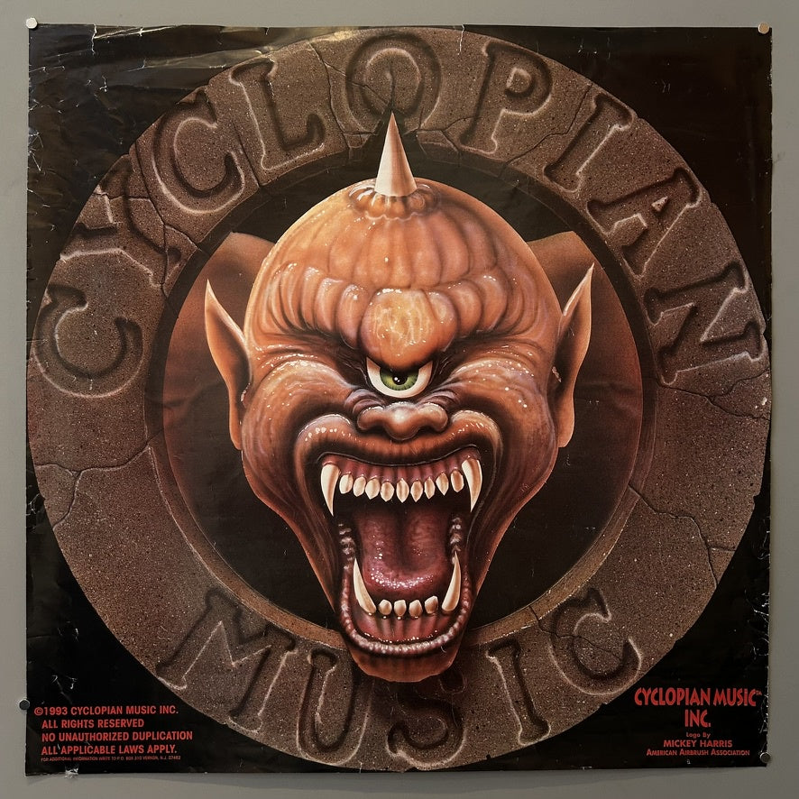 A square image featuring the logo of "CYCLOPIAN MUSIC INC." The logo depicts a monstrous, one-eyed, orange-skinned head with large fangs and pointed ears, emerging from a textured, circular background that resembles stone.
