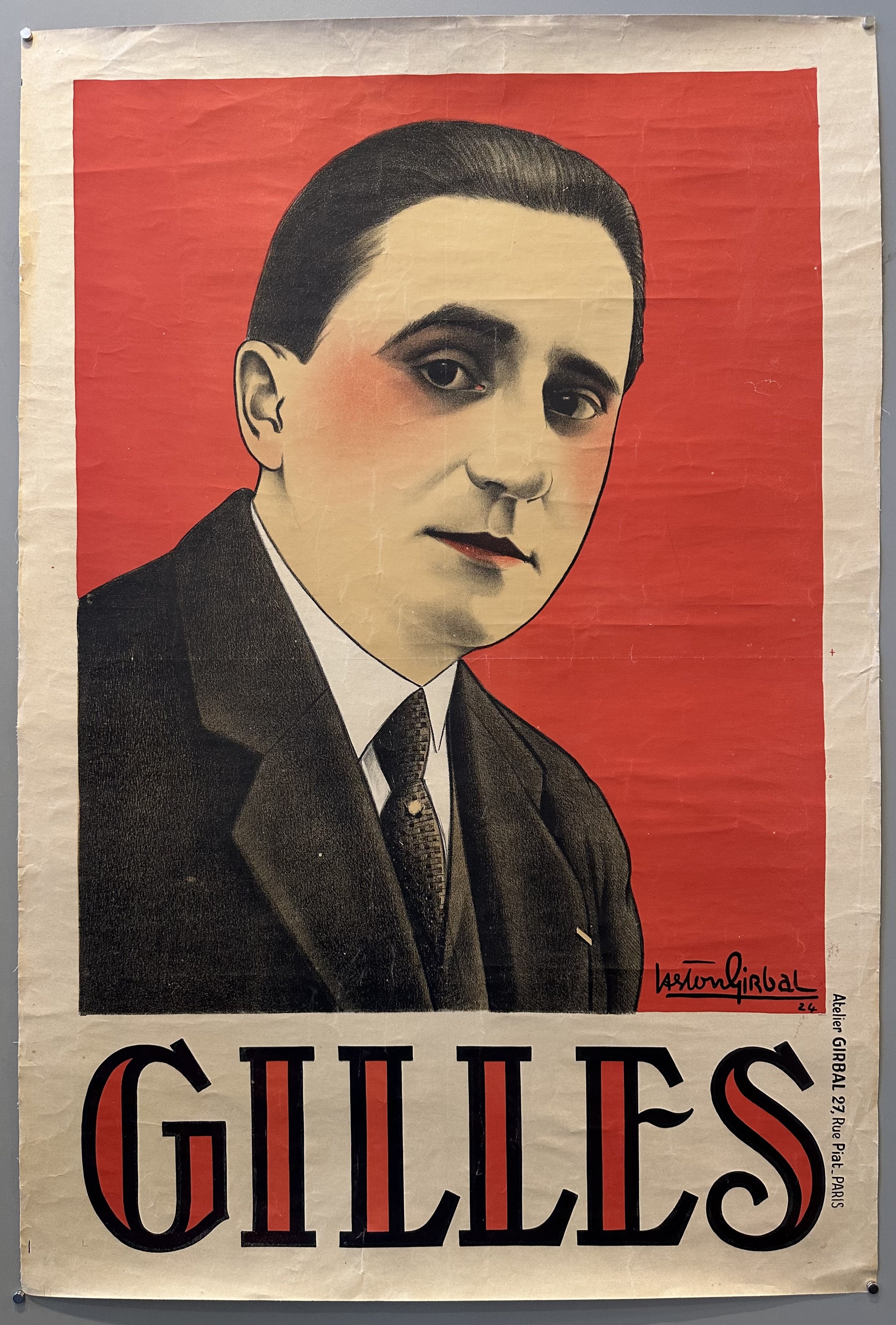 There is a man in a black suit in the center of a red background with the bold text below saying "GILLES".