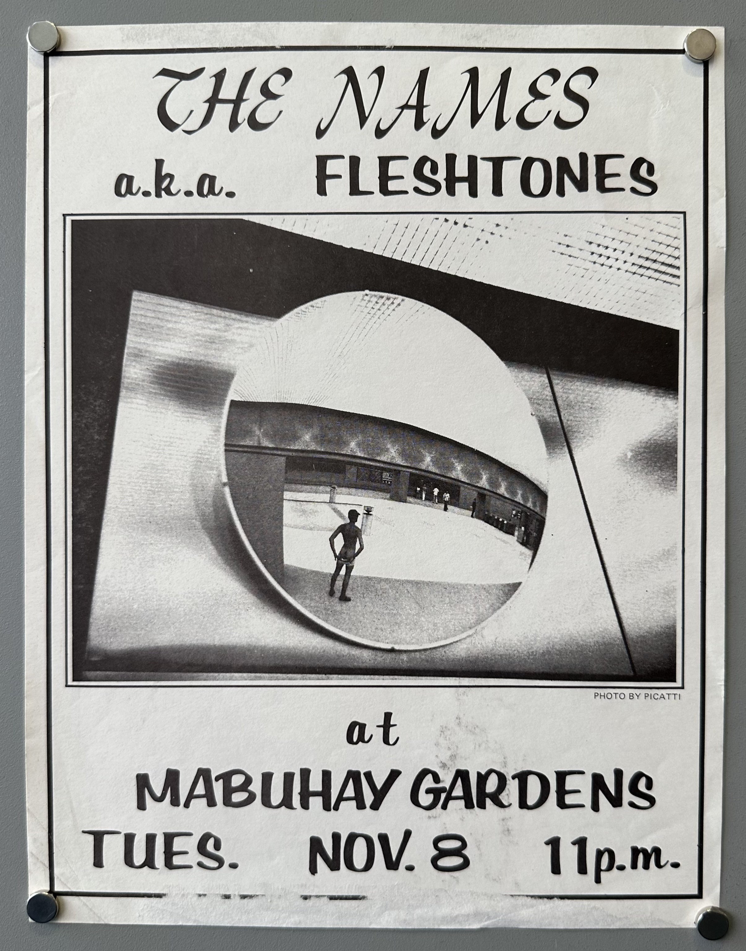 A black and white concert flyer with the text "THE NAMES a.k.a. FLESHTONES" at the top. Below this is a photo with a circular reflection showing a person standing in a large, curved architectural space. Under the photo, the text reads "at MABUHAY GARDENS TUES. NOV. 8 11p.m." The photo is credited as "PHOTO BY PICATTI."