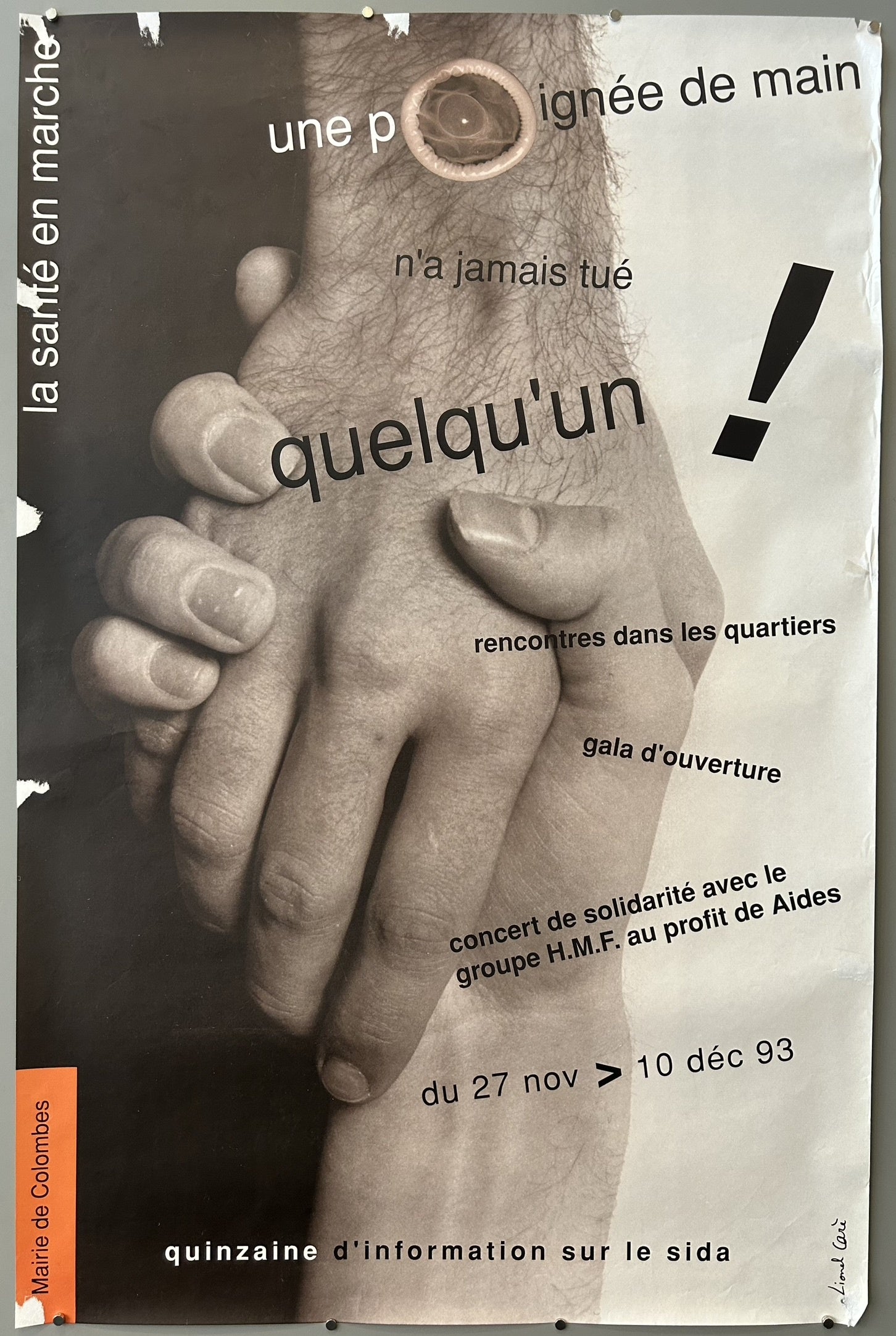 The poster features a prominent image of two hands clasped in a handshake, reinforcing the message that casual physical contact is safe. A condom is subtly integrated into the design, likely symbolizing safe practices.