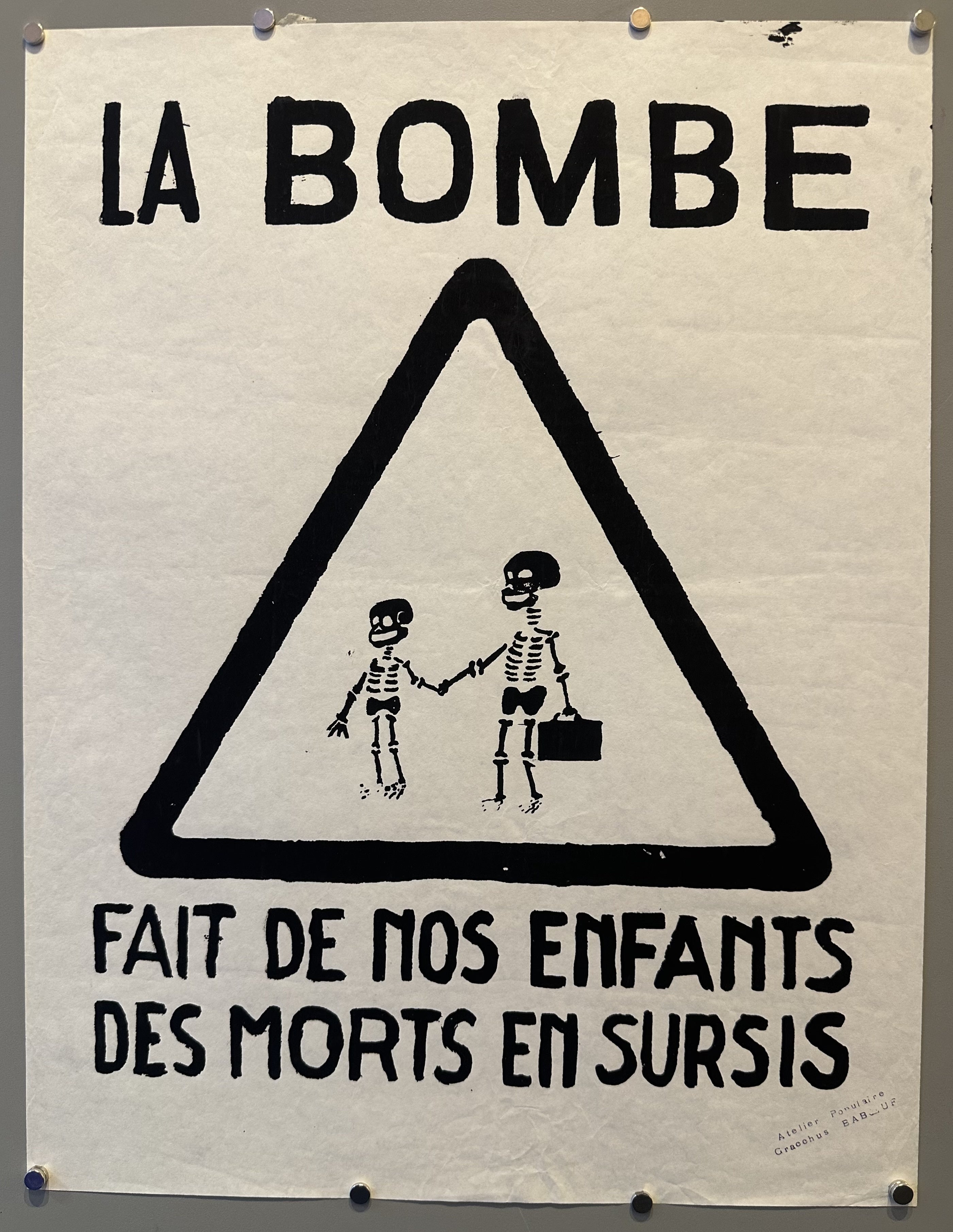 Two skeletons hold hands with a caution triangle around them and black text above and below them.