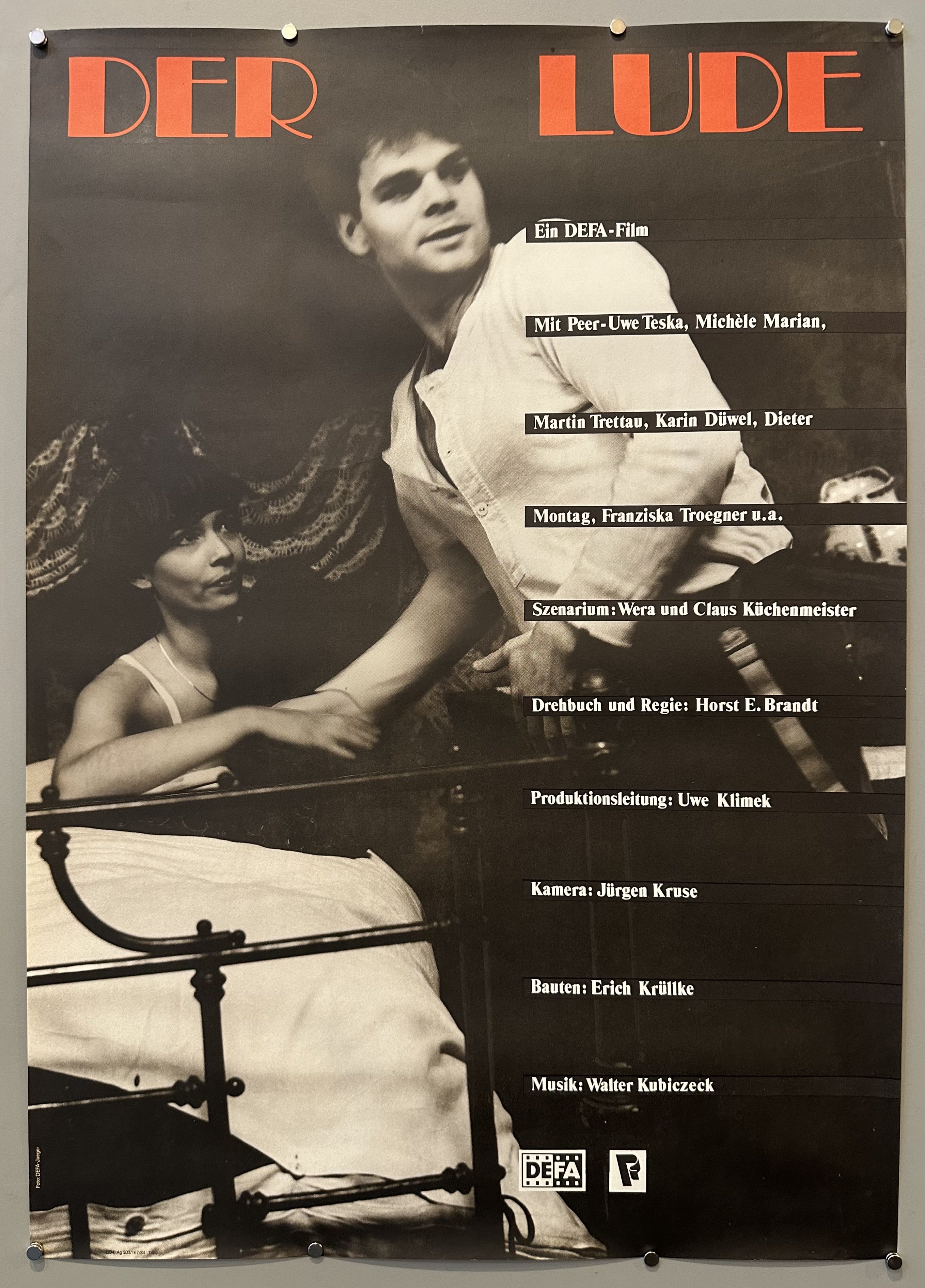Black and white photograph of two actors mid-scene during Der Lude, a German film, with the cast and crew's names listed on right-hand side.
