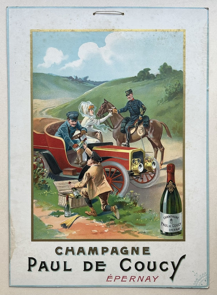 This vintage poster advertises Champagne Paul De Coucy from Épernay, France. It depicts a group of people enjoying a day out in the countryside. A couple is seated in a red car, while a man in uniform rides a horse alongside them. Another man is kneeling beside the car, seemingly unpacking a picnic basket. The scene is set against a backdrop of rolling hills and a cloudy sky