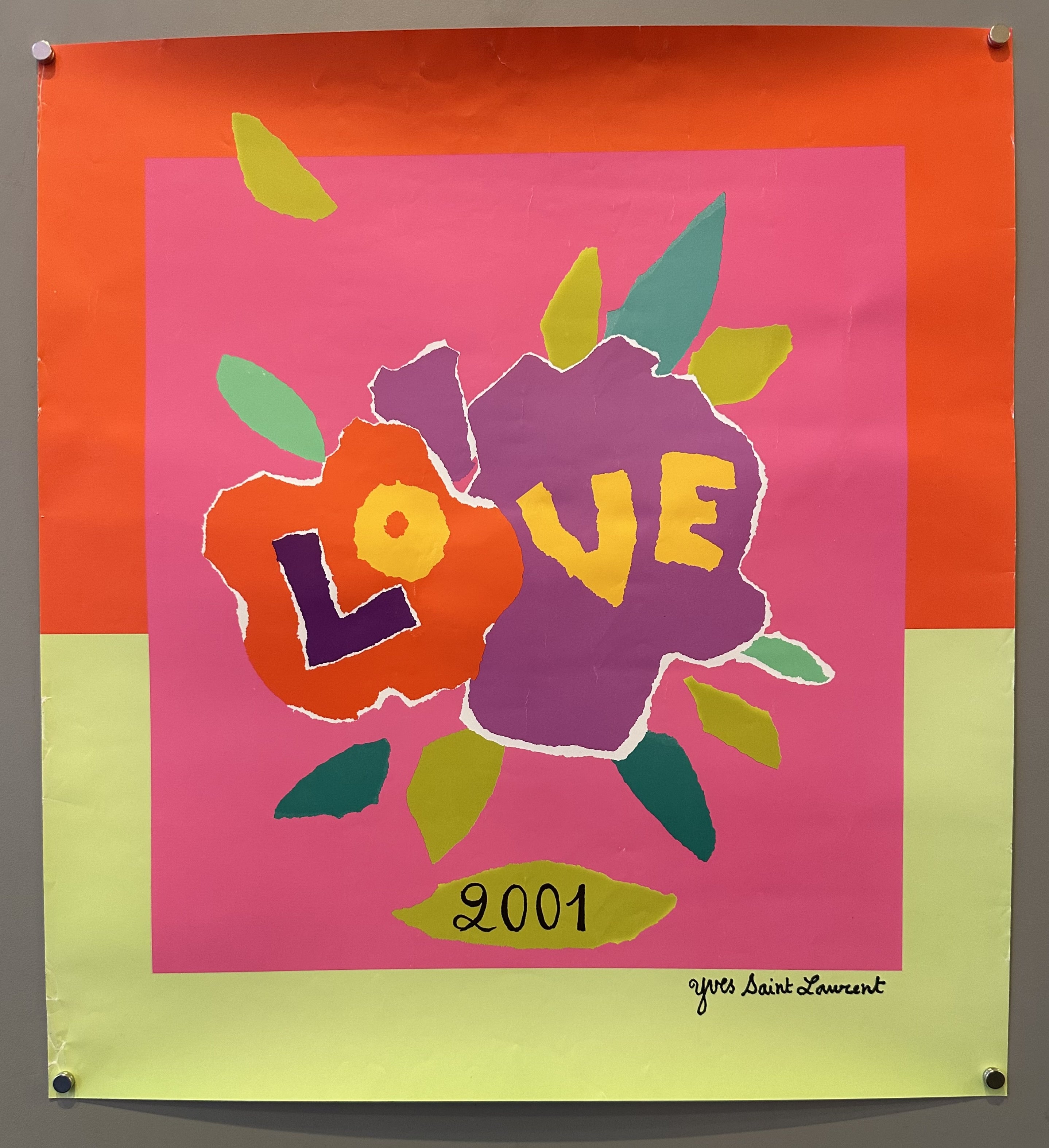 The word "LOVE" appears in large, colorful, overlapping letters at the center, with the number "2001" beneath it. In the bottom right corner, the text "Yves Saint Laurent" is written in small, black letters.