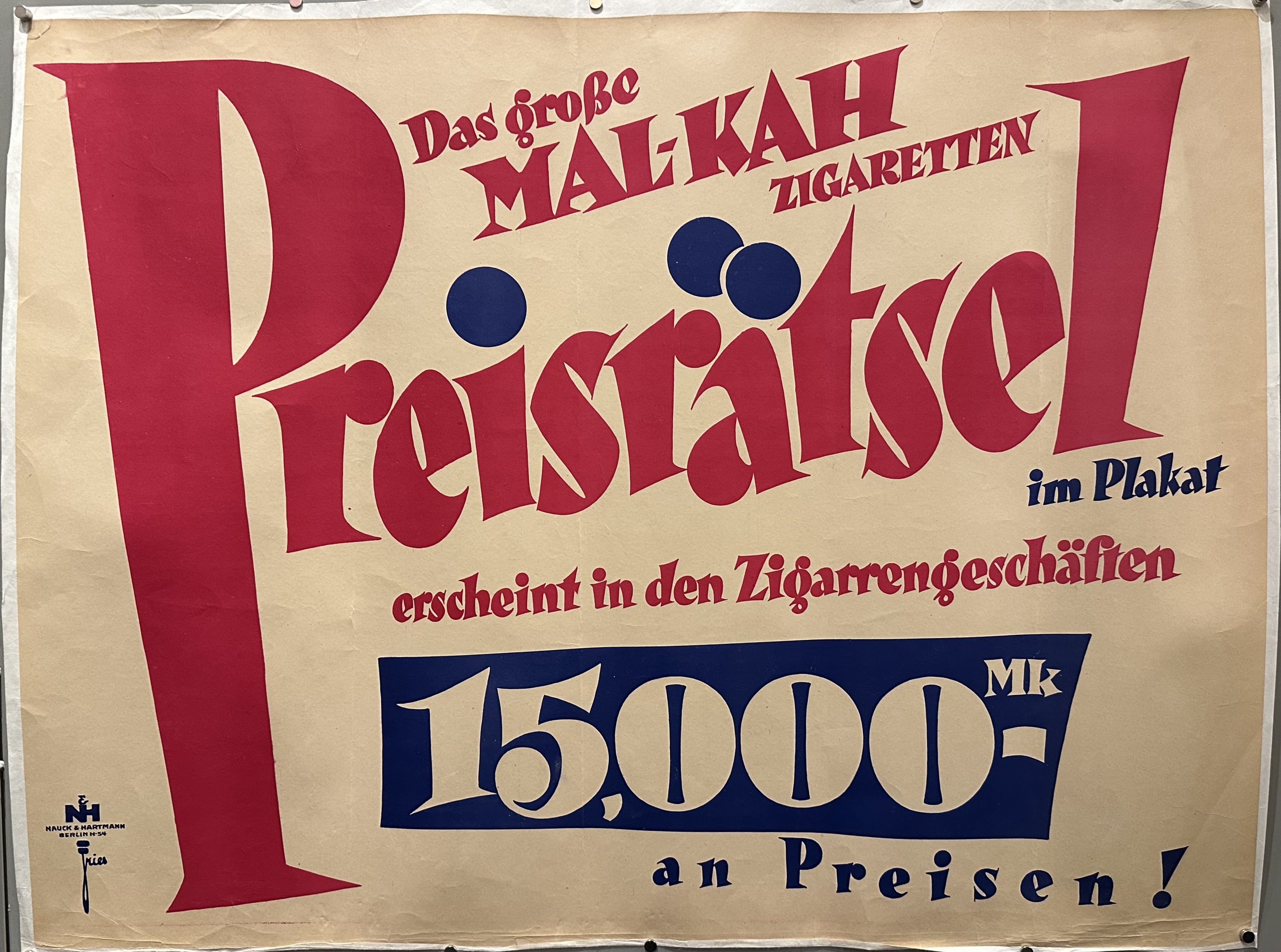 Pink and blue German text against beige background for advertisement for cigarettes.
