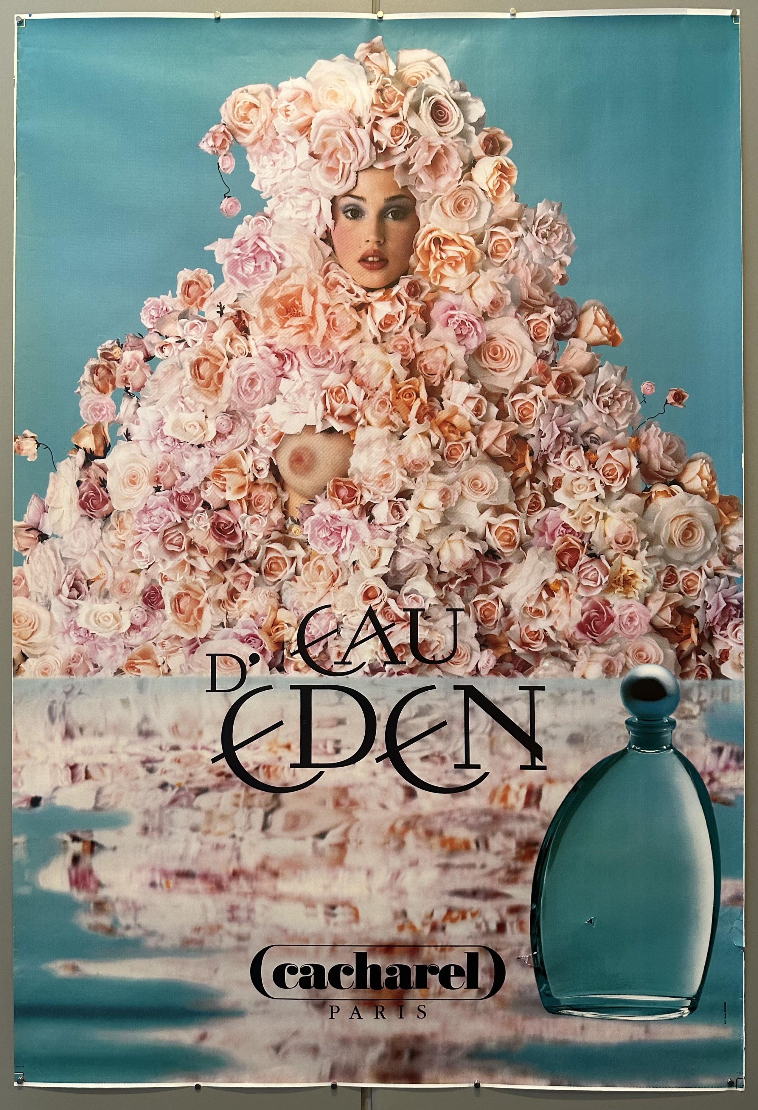 Nude front-facing model covered in roses against teal background for Eau d'Eden advertisement.