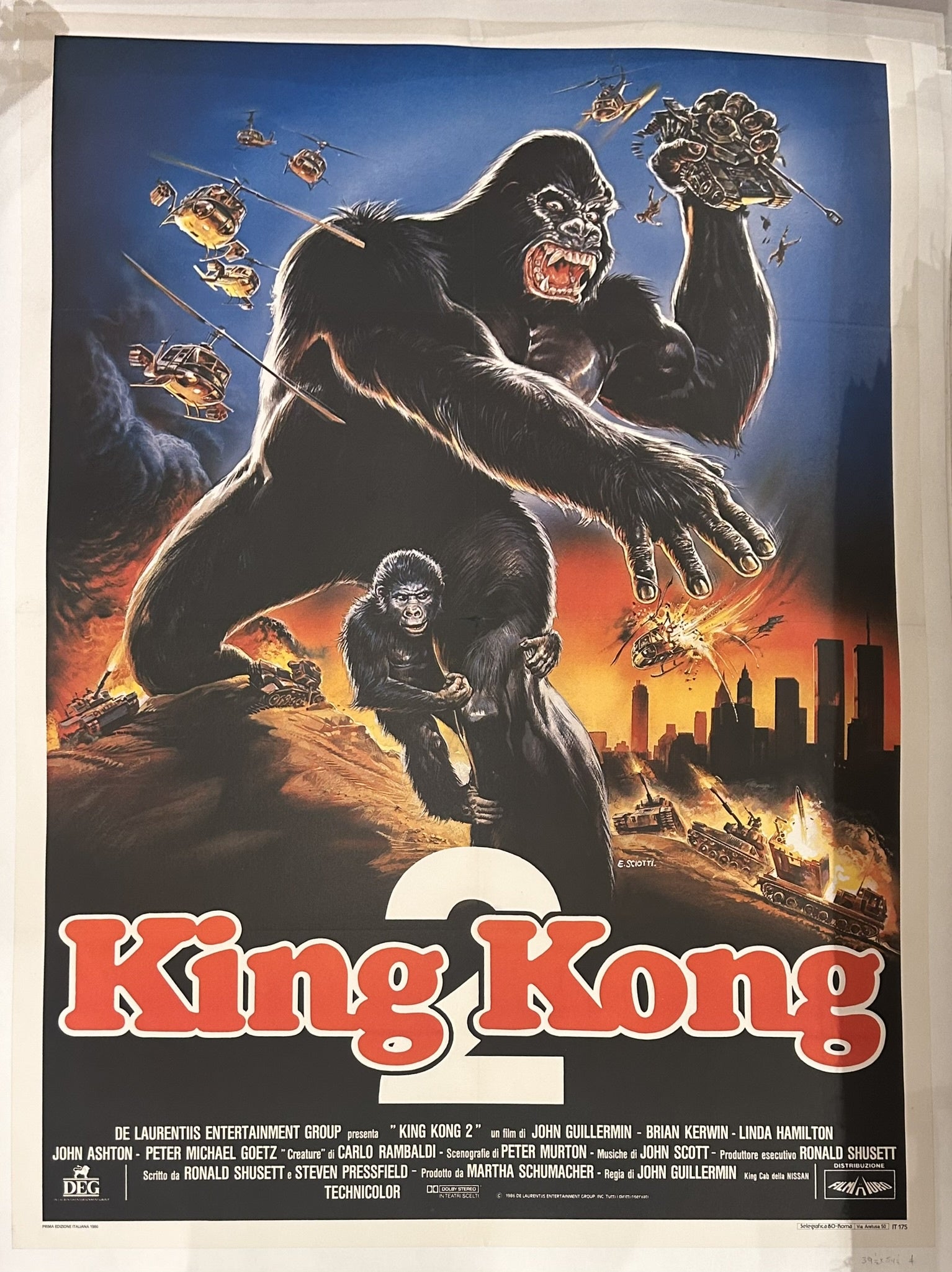 A movie poster for 'King Kong 2' (also known as 'King Kong Lives'), featuring a giant gorilla, King Kong, holding a smaller female gorilla, Lady Kong, with military helicopters and tanks in the background and a burning city skyline