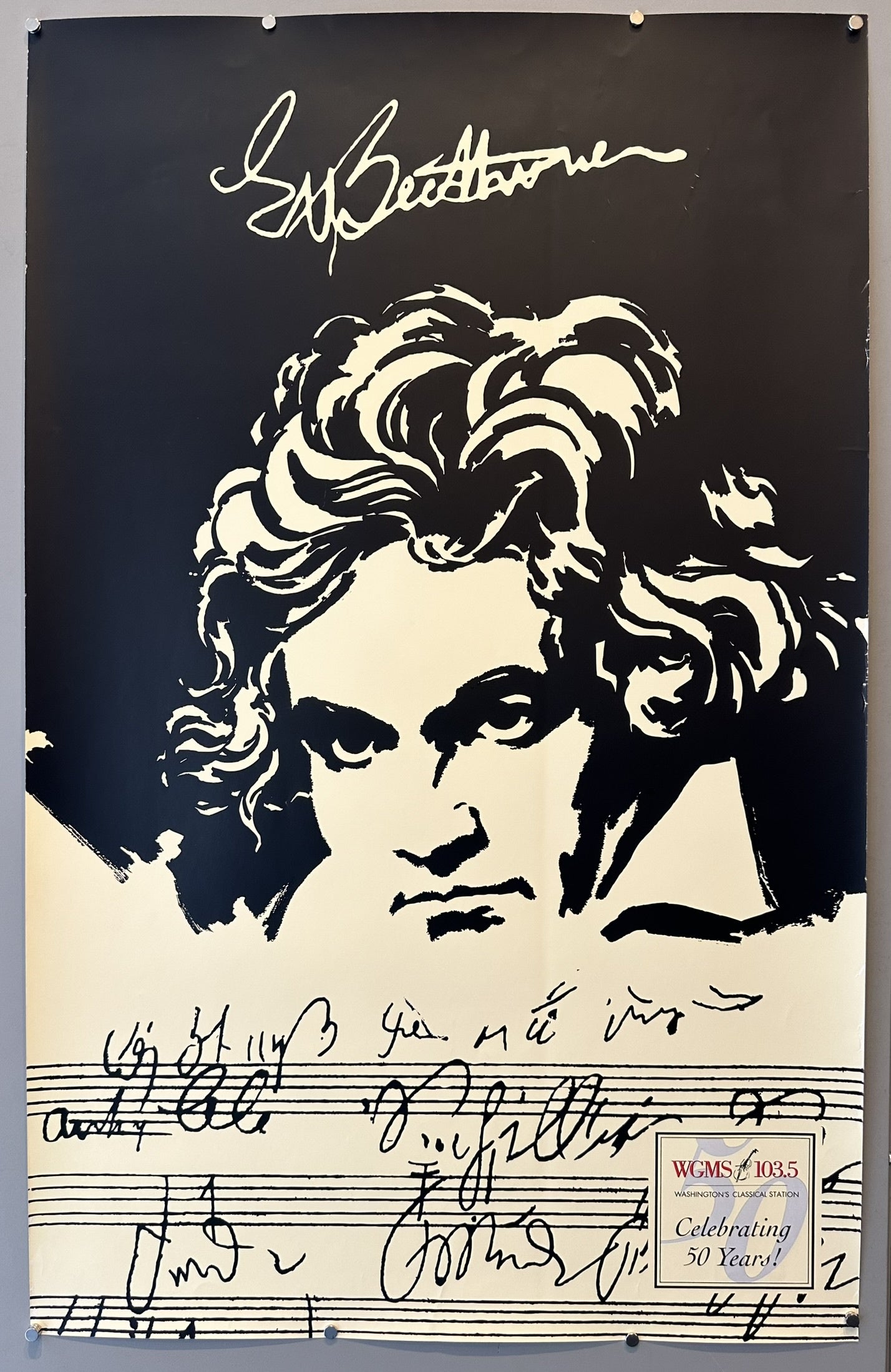 A poster featuring a stylized black and white portrait of Ludwig van Beethoven, with his signature and musical notation at the top and bottom, respectively. The poster also includes the text "WCMS 103.5 Celebrating 50 Years!" at the bottom right.
