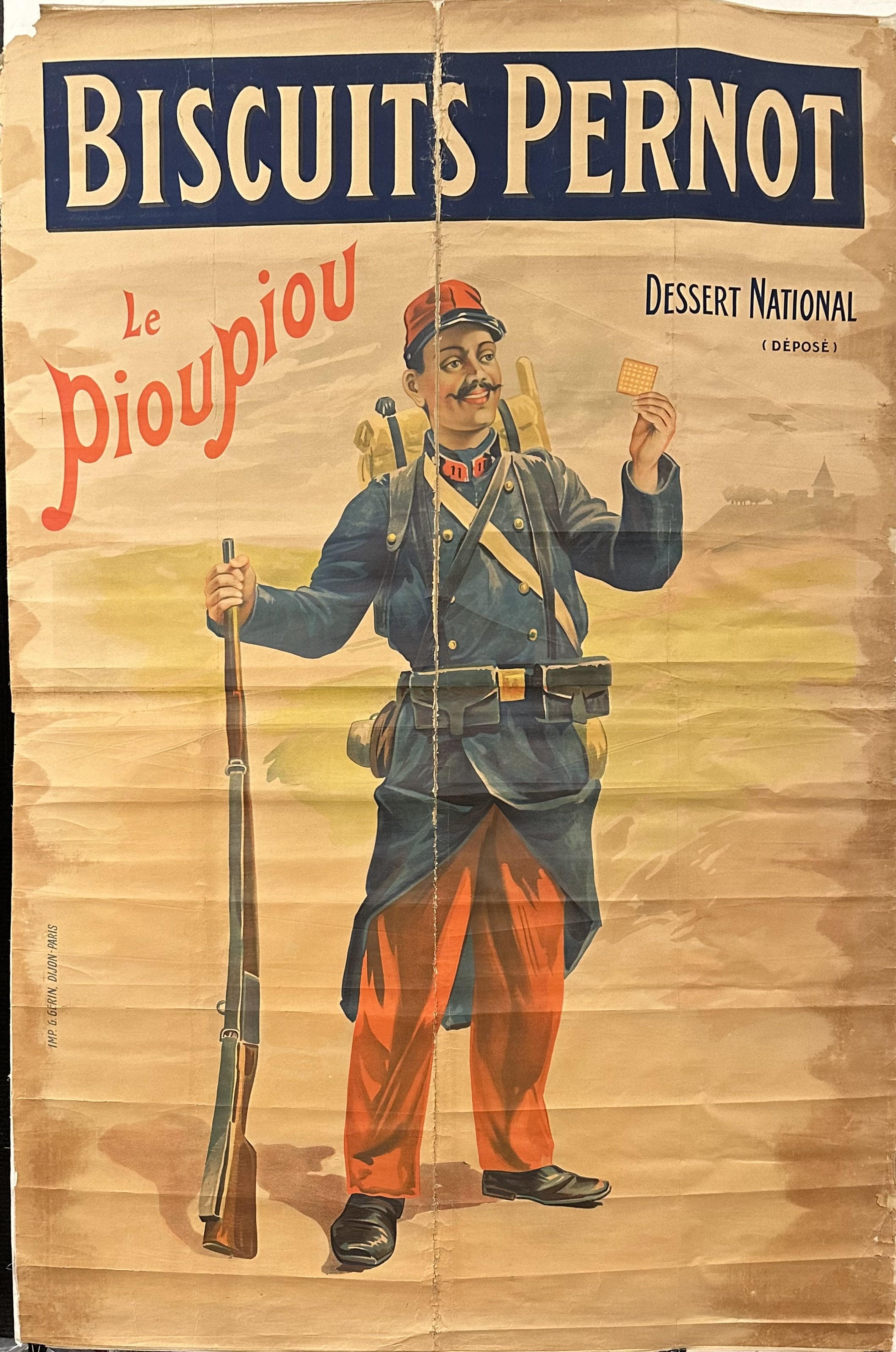 A soldier holds up a biscuit with a rifle in his other hand.