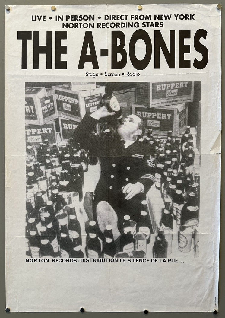 The A-Bones," featuring the text: "LIVE • IN PERSON • DIRECT FROM NEW YORK NORTON RECORDING STARS THE A-BONES Stage • Screen • Radio." Below the text is a black and white image of a man in a uniform drinking from a bottle, surrounded by numerous bottles and crates labeled "RUPPERT Beer." The bottom of the poster reads: "NORTON RECORDS: DISTRIBUTION LE SILENCE DE LA RUE