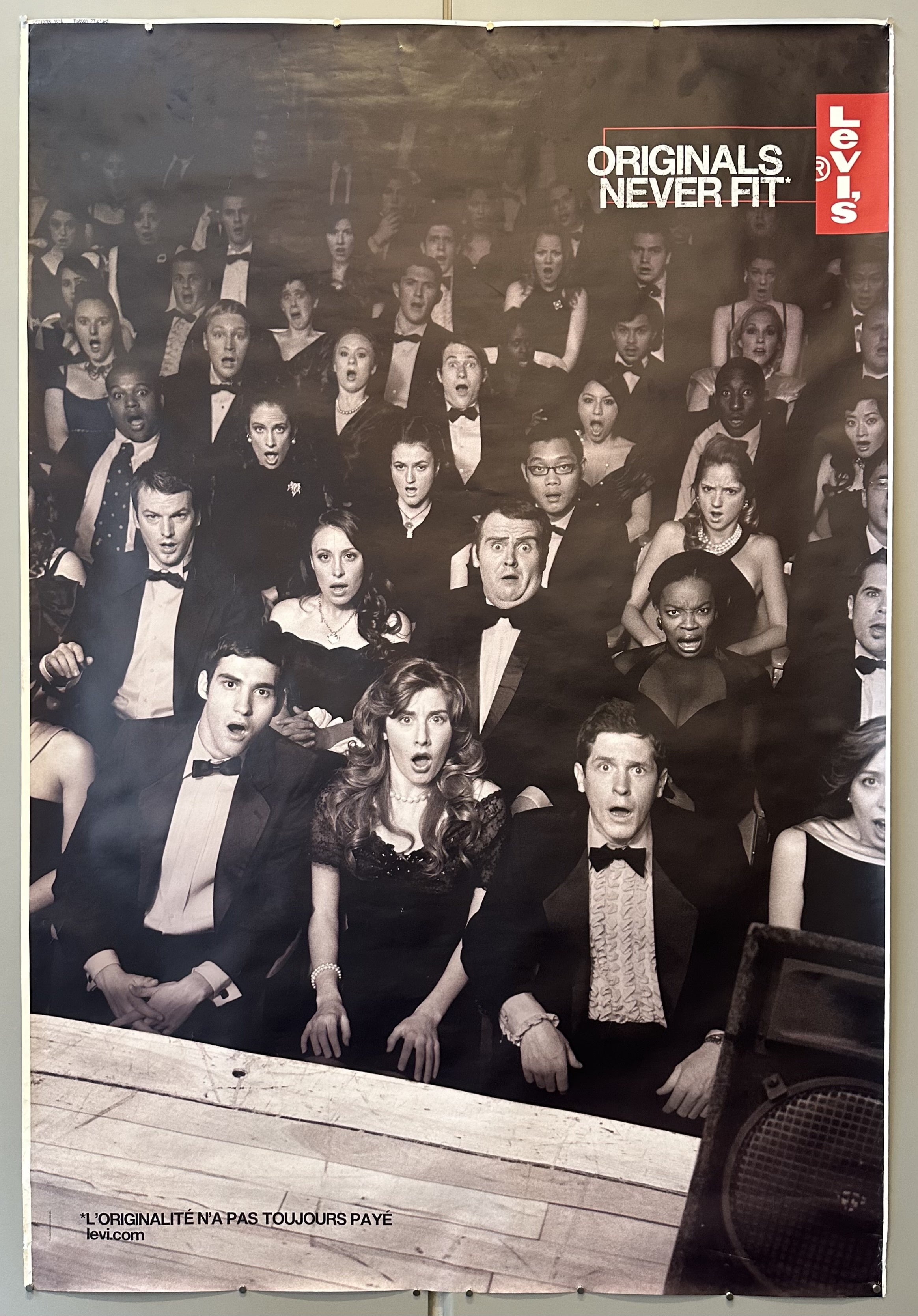 Black and white photograph of a formally-dressed audience all looking shocked at someone on stage in Levi's ad.