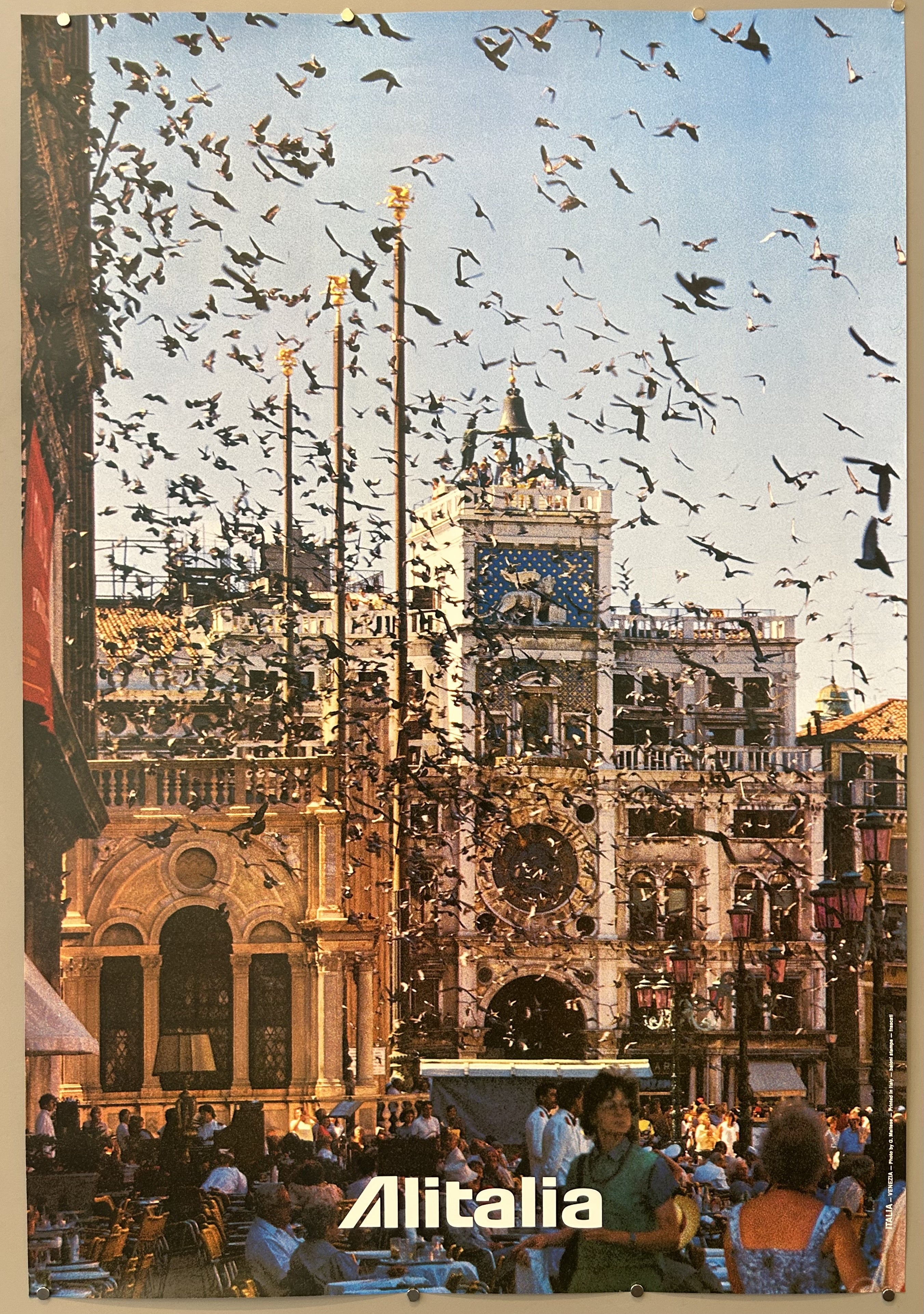 Photograph of city sidewalk in Venice in vintage travel poster from Alitalia, with Alitalia logo along bottom.