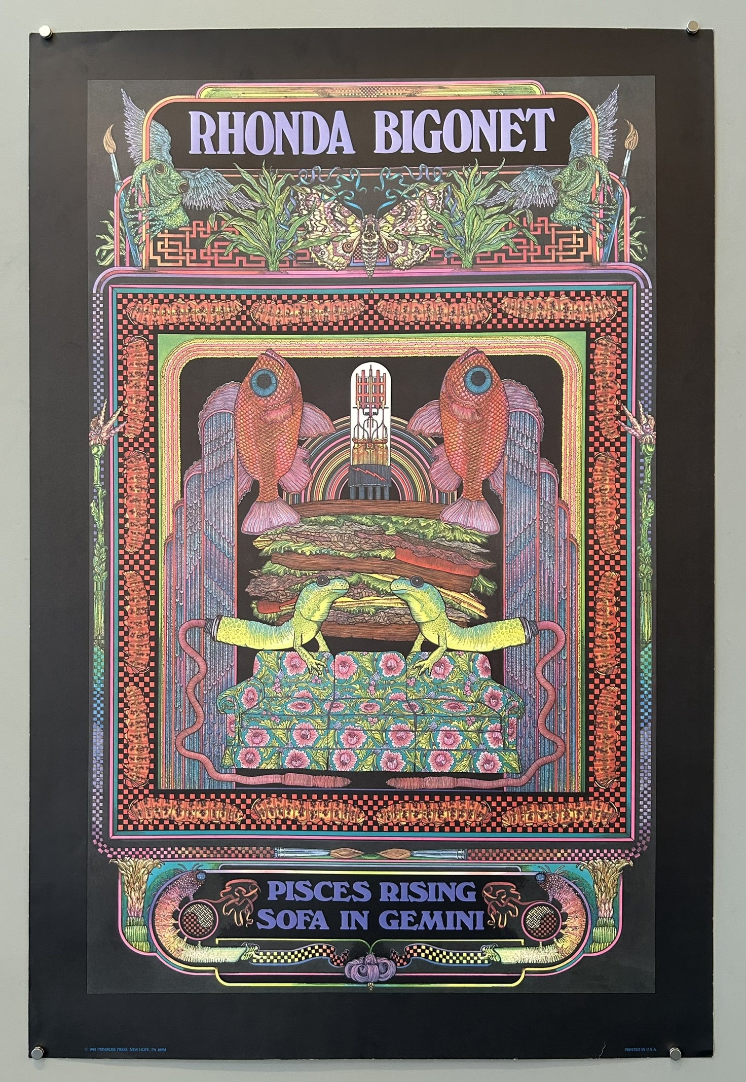 A vibrant, psychedelic poster with the title "RHONDA BIGONET" at the top. The central image features two large, orange-red fish facing inward above a stacked arrangement of elements resembling a hamburger or layered structure, with two green lizard-like creatures interacting in the foreground.