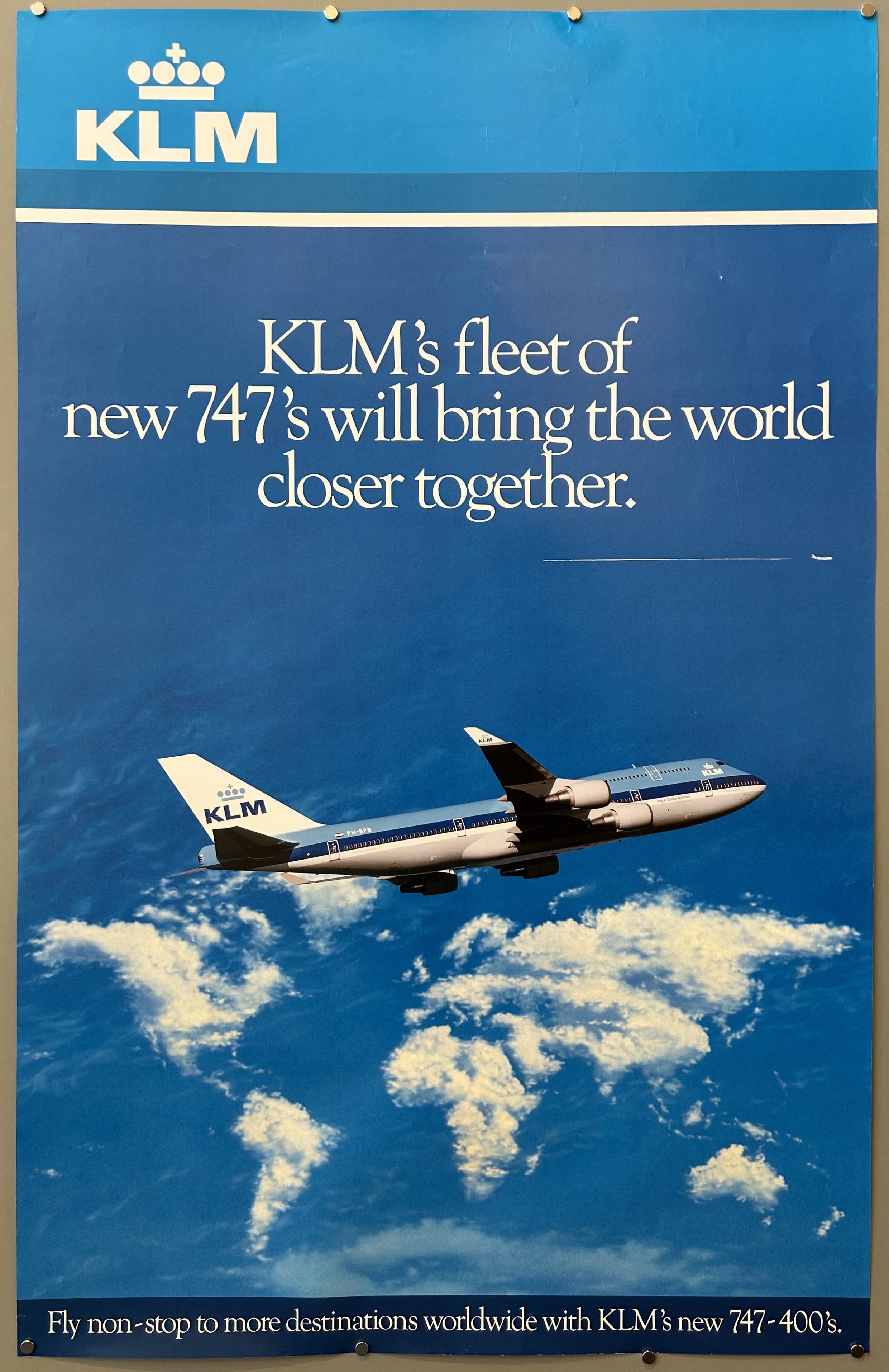 KLM logo at top. Below, airplane (Boeing 747) in KLM livery flies above clouds that form the shape of a world map