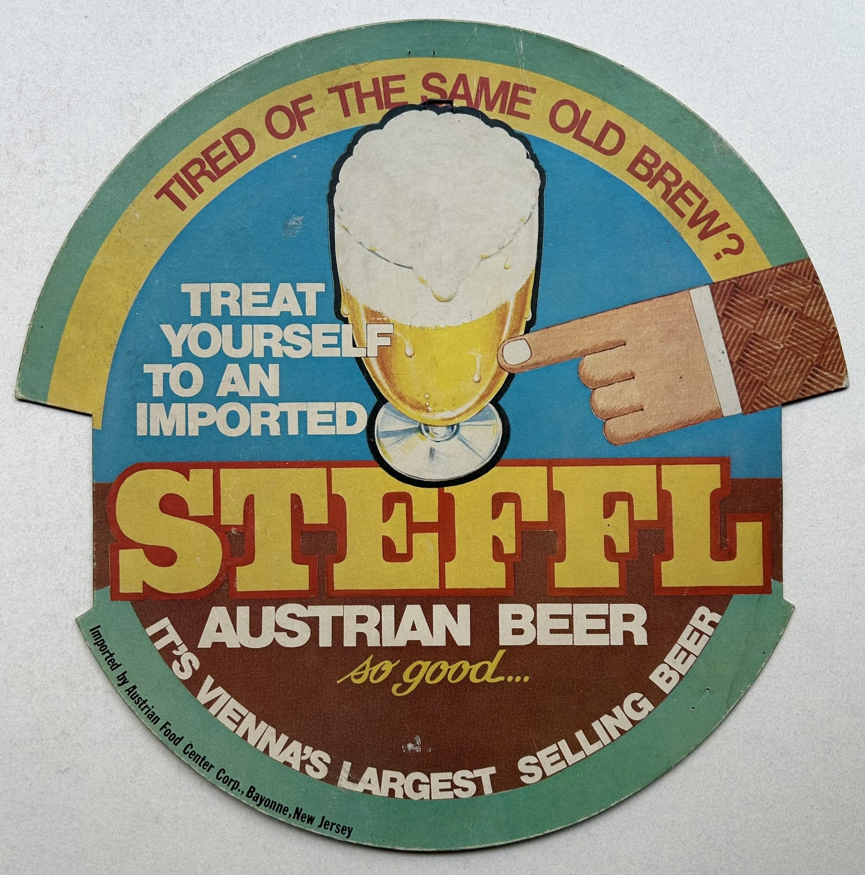 This image is an advertisement for Steffl Austrian Beer. It shows a circular beer coaster with a hand pointing towards a glass of beer. The text on the coaster reads "Tired of the same old brew? Treat yourself to an imported Steffl Austrian Beer. It's Vienna's largest selling beer." The coaster also mentions that the beer is imported by Austrian Food Center Corp., Bayonne, New Jersey.