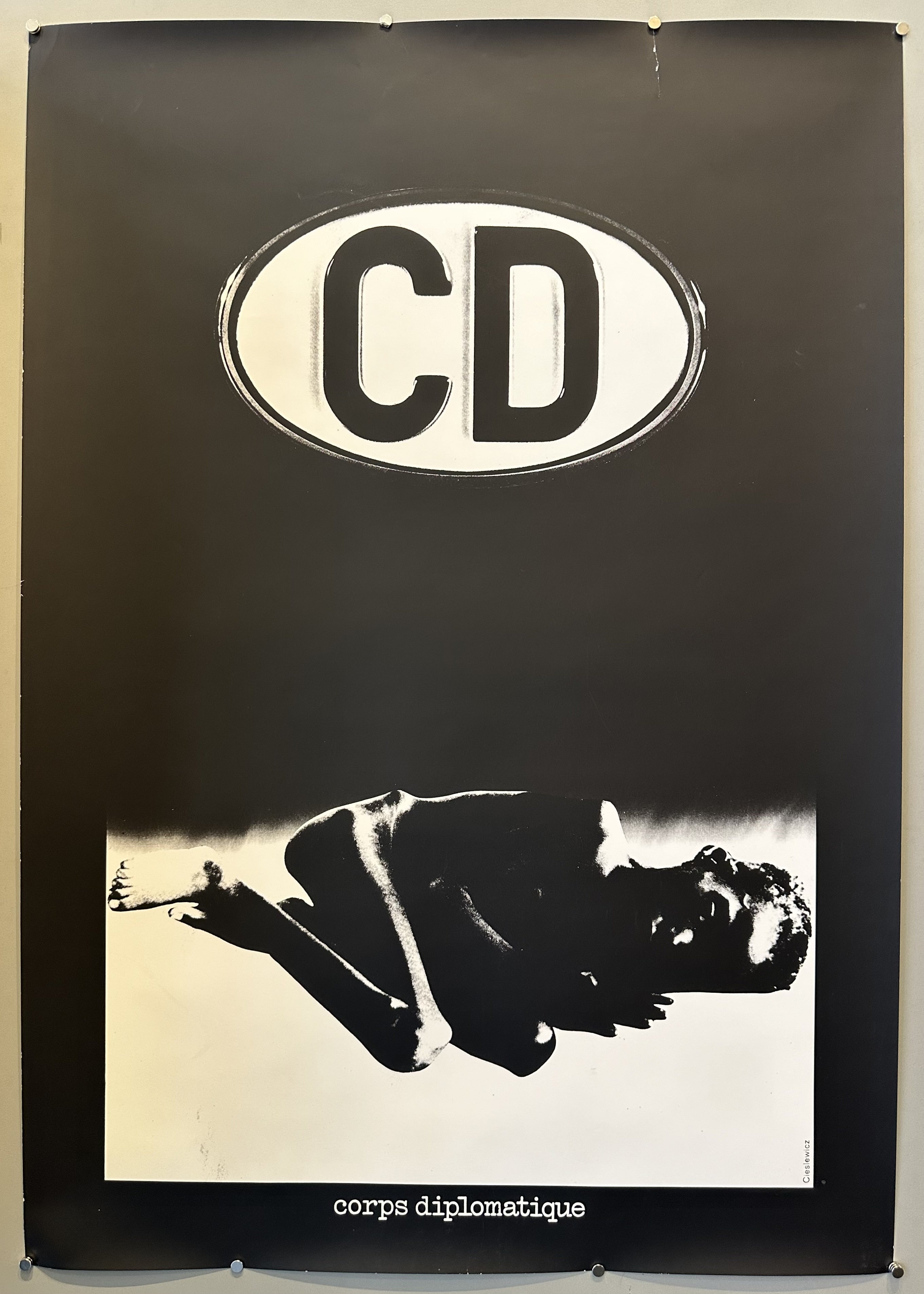 A small emaciated child cowers on the ground in this black poster with 'CD' written above in white.