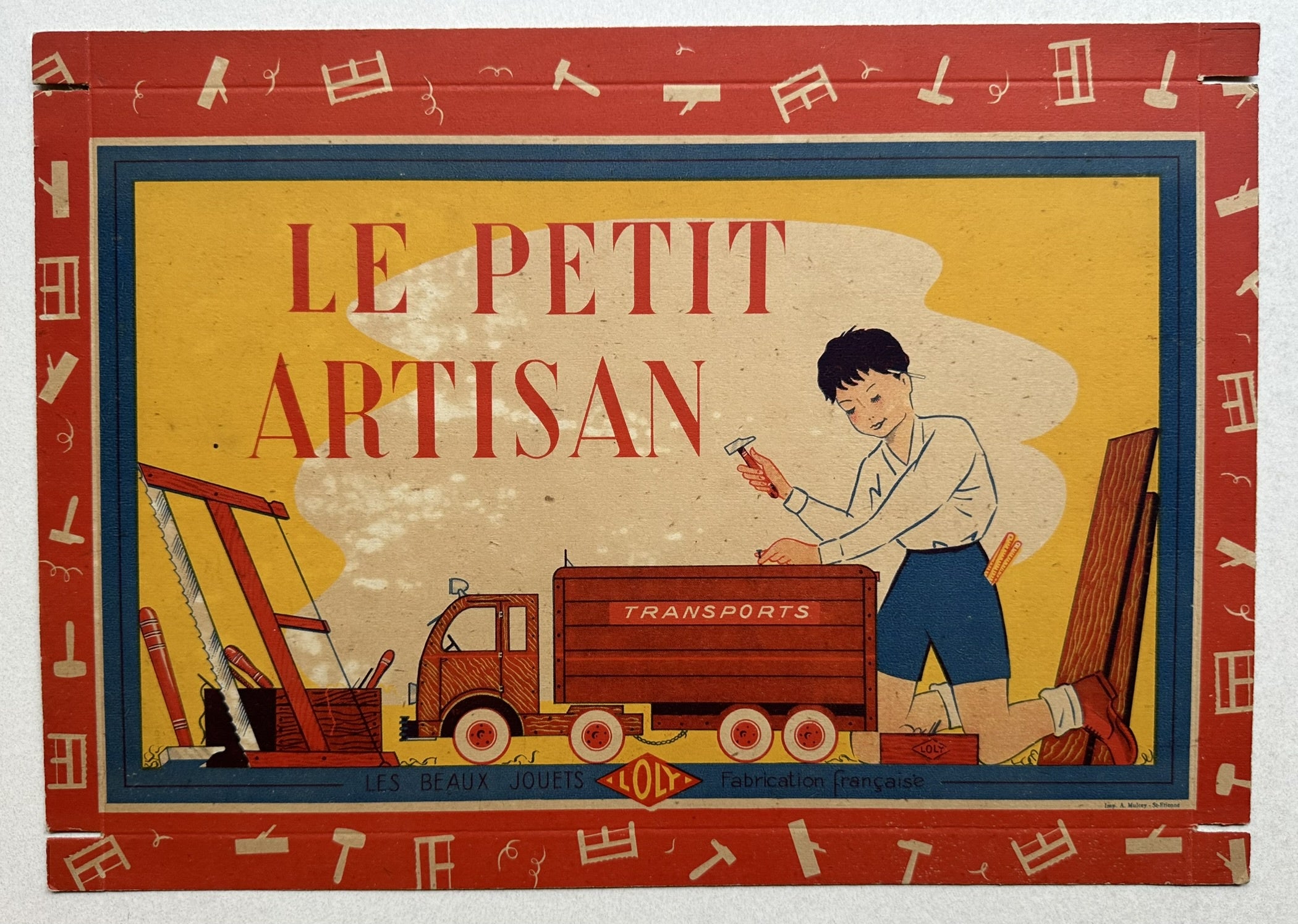 An image of a vintage French toy box, titled "Le Petit Artisan," depicting a young boy hammering wood next to a toy truck, with various tools and construction elements in the background.
