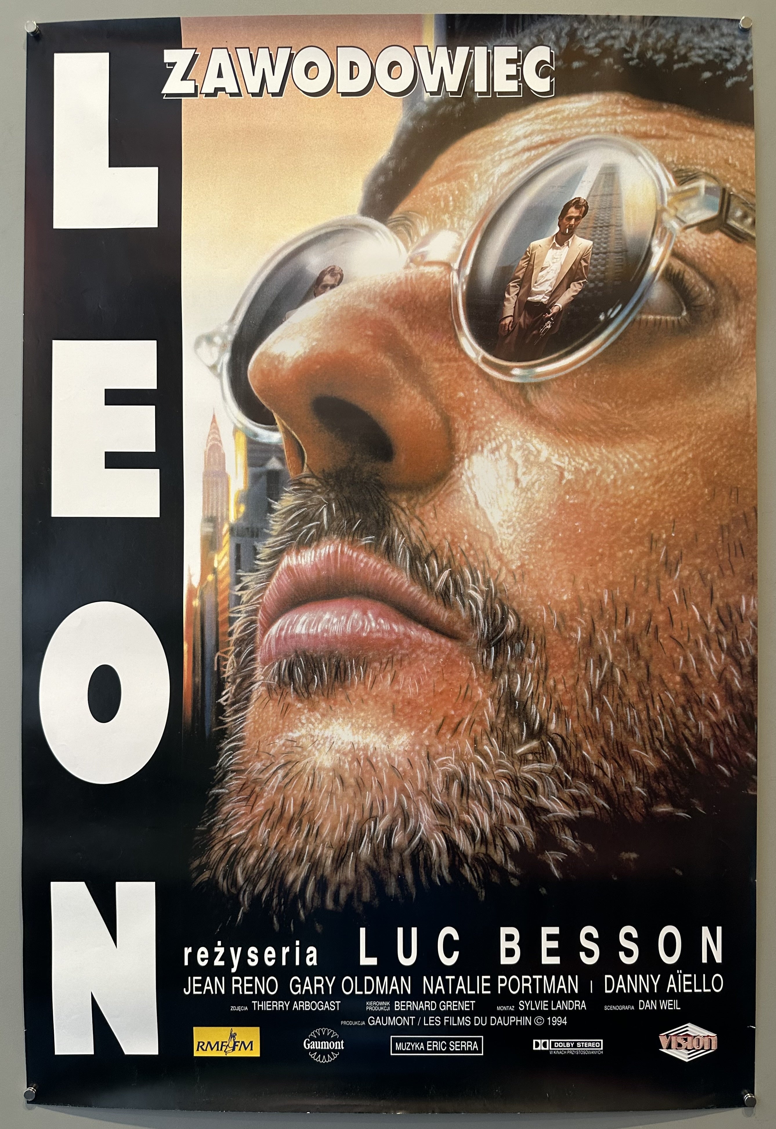 A movie poster for the 1994 film "Léon: The Professional". The poster features Jean Reno, wearing sunglasses, in the foreground with a blurred image of a man on his lenses.